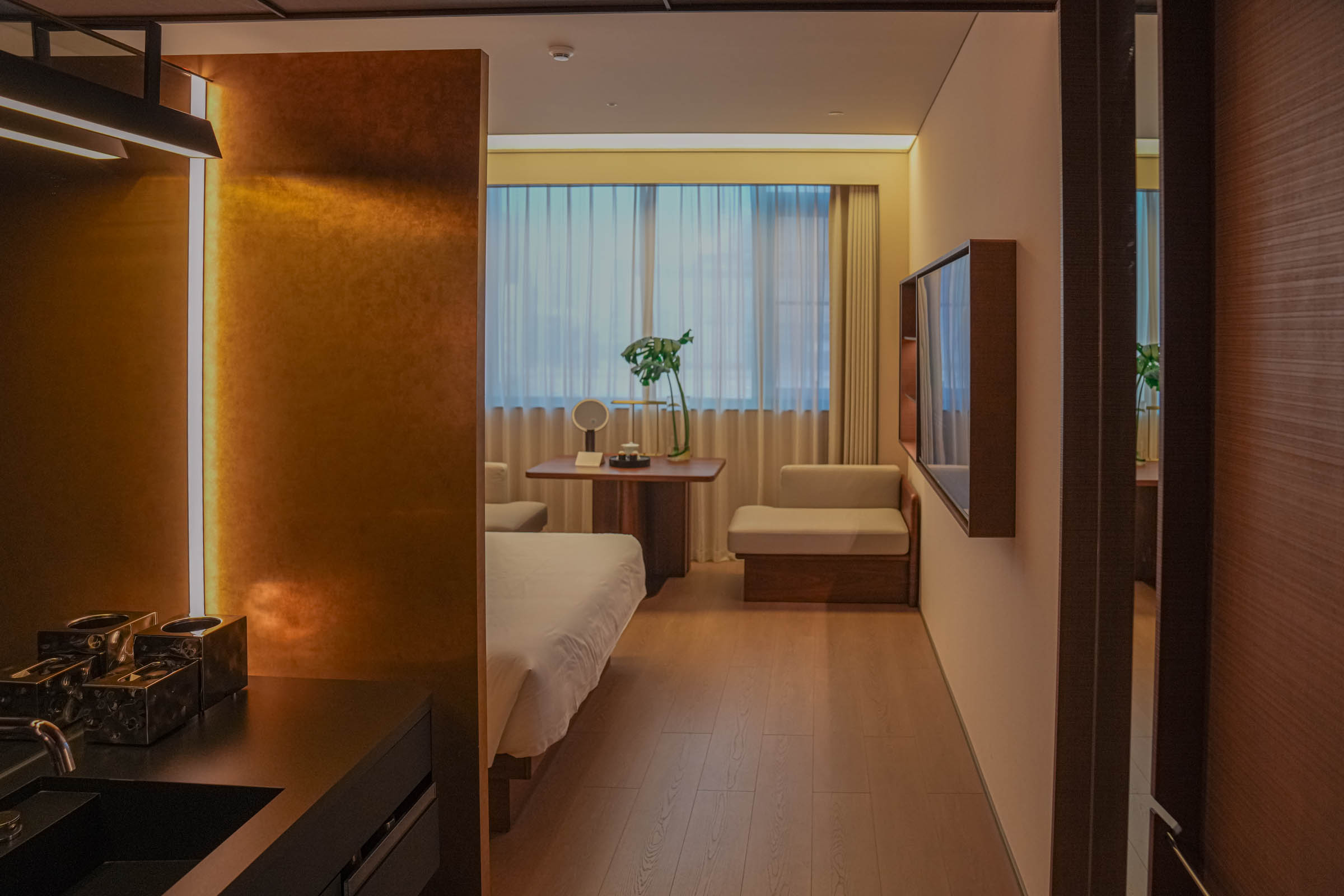 A spacious, minimalist hotel room at SAVHE Atour Hotel North Bund Shanghai decorated in neutral tones, with a large bed, contemporary furniture, and floor-to-ceiling windows – creating a serene retreat amid the urban bustle.