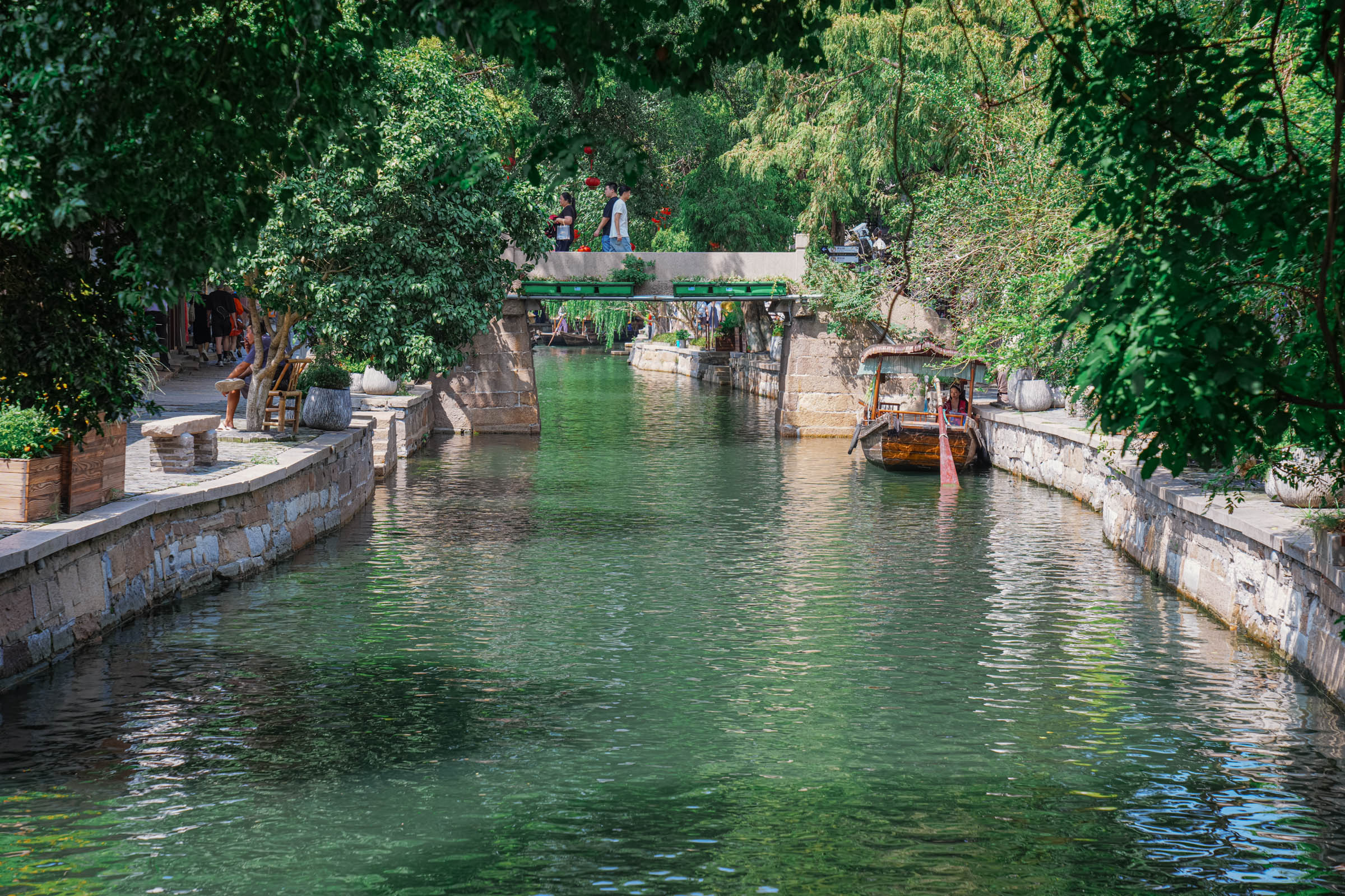 A narrow stone-paved alleyway in Zhujiajiao flanked by traditional waterfront homes with wooden shutters and balconies, offering a tranquil view toward the canal as it vanishes around a bend.