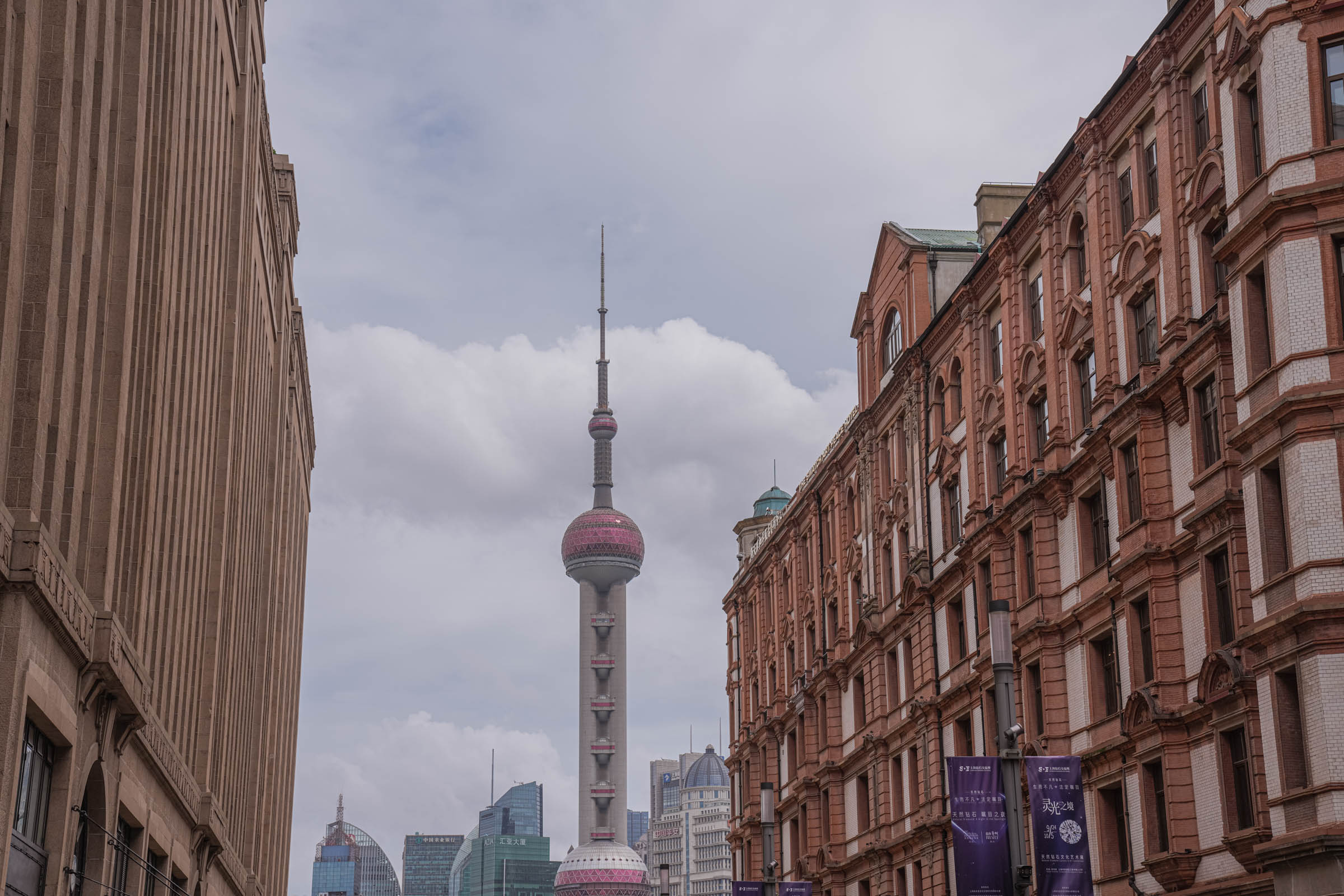 The Bund waterfront at night in Shanghai, with its grand colonial buildings beautifully illuminated in golden light on the west bank, facing the brightly lit modern skyscrapers of Pudong across the river, all reflected in the rippling water.