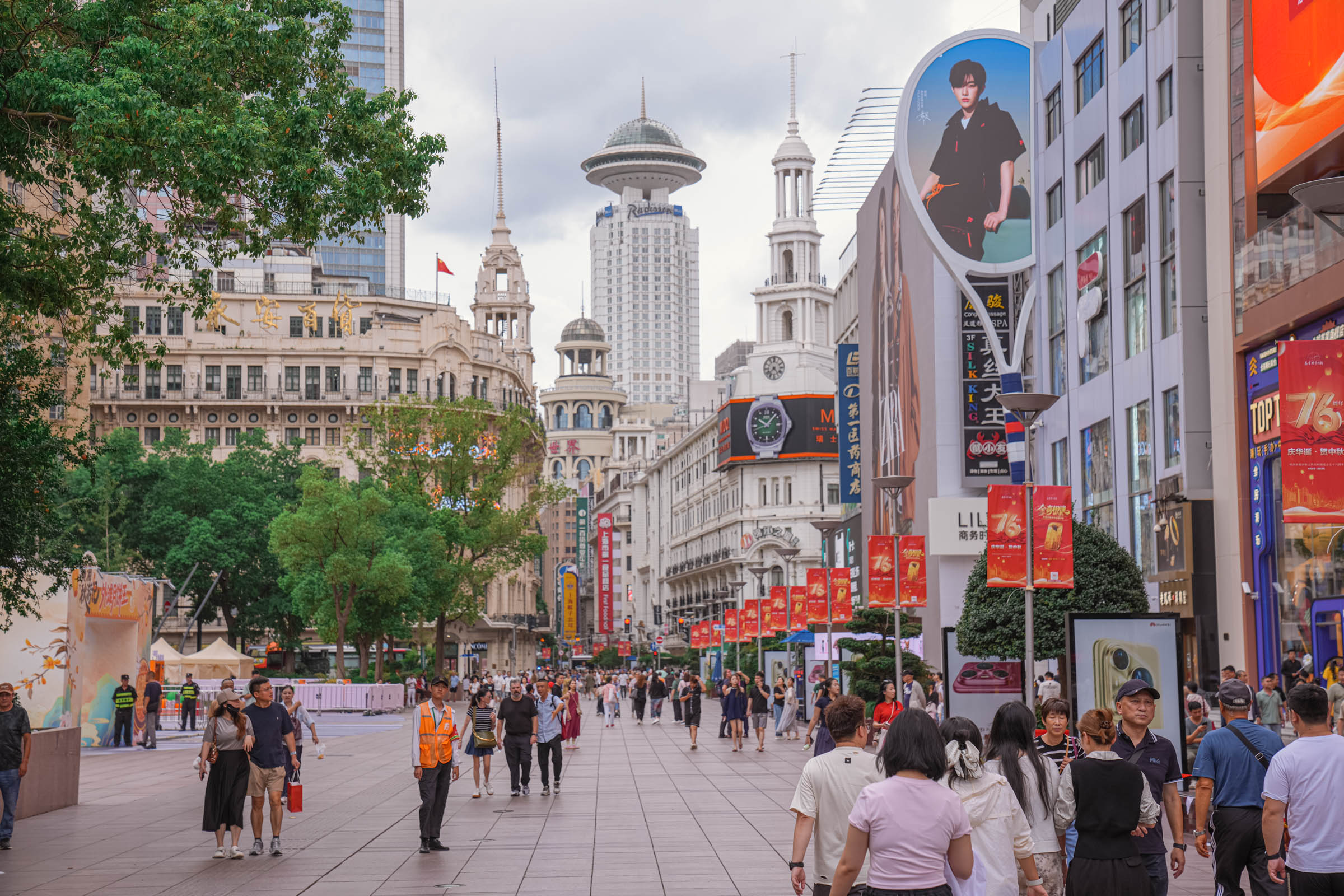 Bustling Nanjing Road in Shanghai at dusk, illuminated by vibrant neon signs and giant LED screens as a sea of shoppers flows through China’s most famous shopping street, showcasing the electrifying energy of the city’s nightlife.