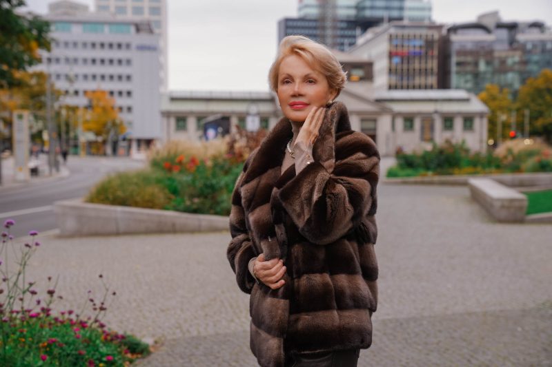Elegant woman in brown fur coat with gold jewelry