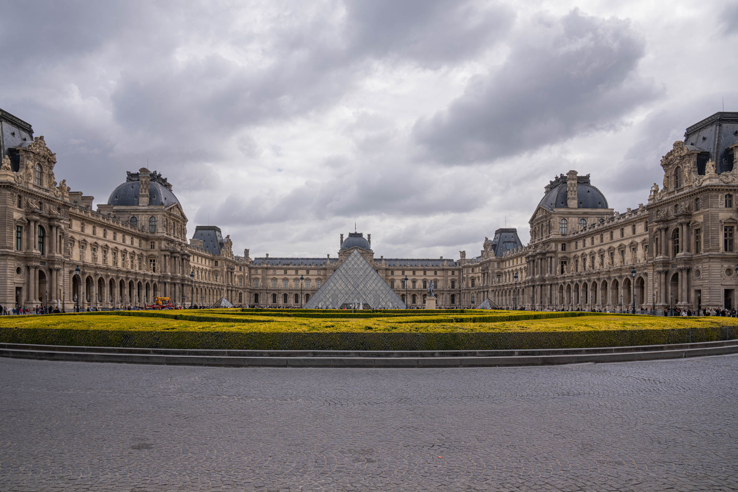 The glass pyramid of the Louvre beside the equestrian statue of Louis XIV in Paris