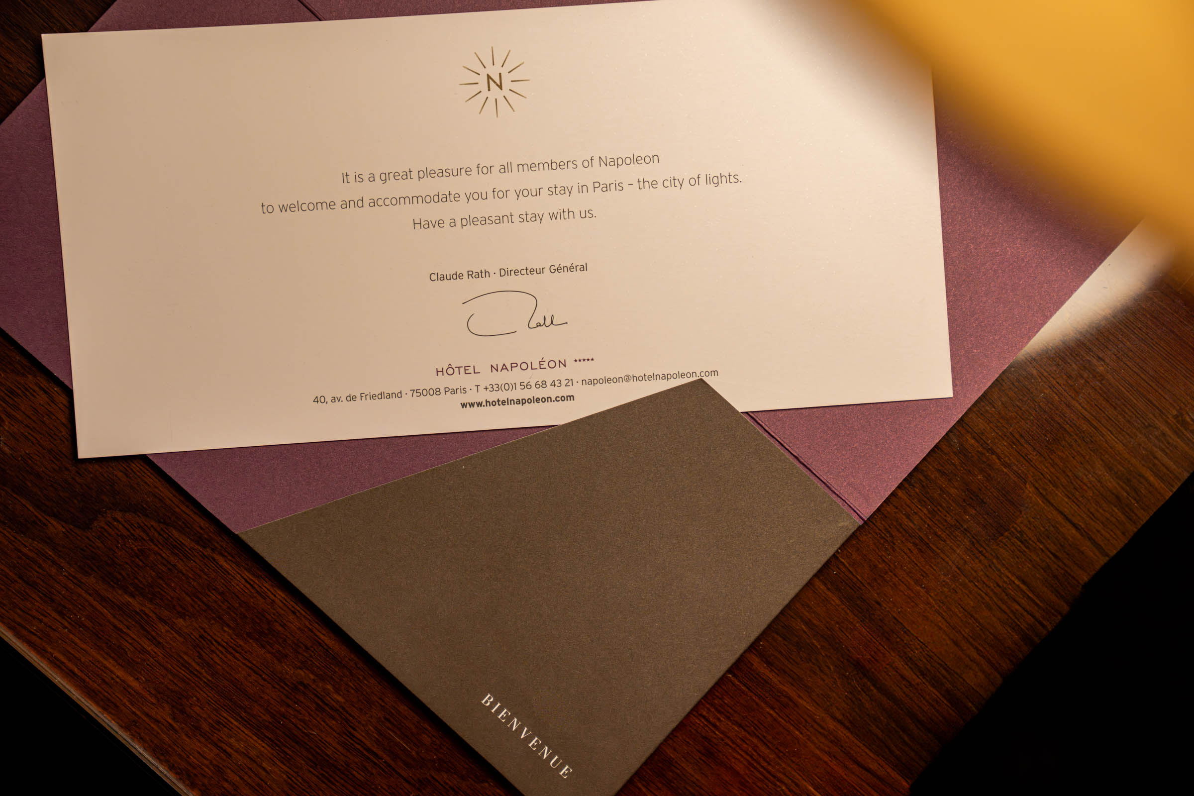 Personal welcome card signed by general manager Claude Rath at Hôtel Napoléon Paris, beside a "Bienvenue" envelope