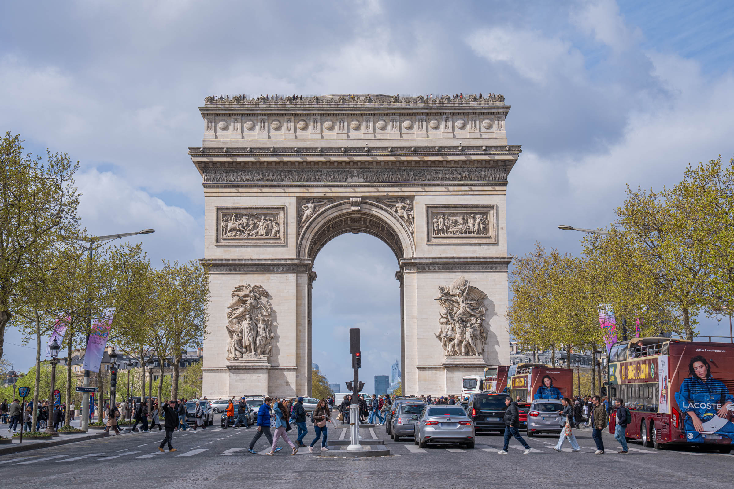 The Arc de Triomphe in Paris seen from the Champs-Élysées, its reliefs sharp against a grey sky