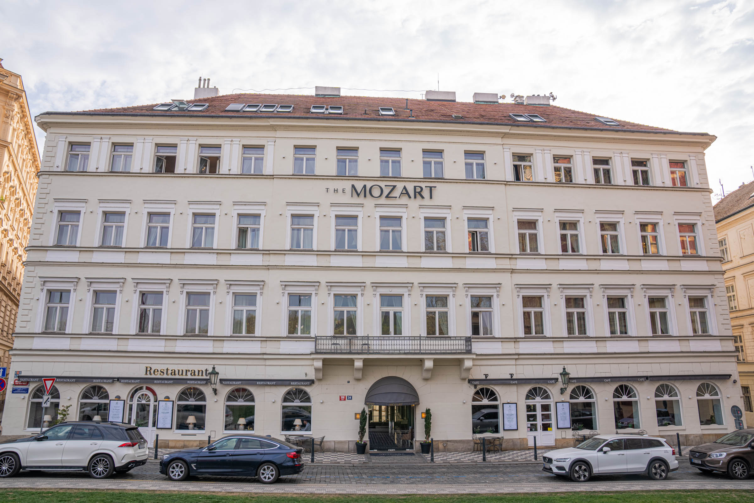 The Mozart Prague hotel exterior facade an elegant cream-colored 19th-century neoclassical building on Karoliny Svetle street with the hotel restaurant and café at street level, located one minute walk from Charles Bridge