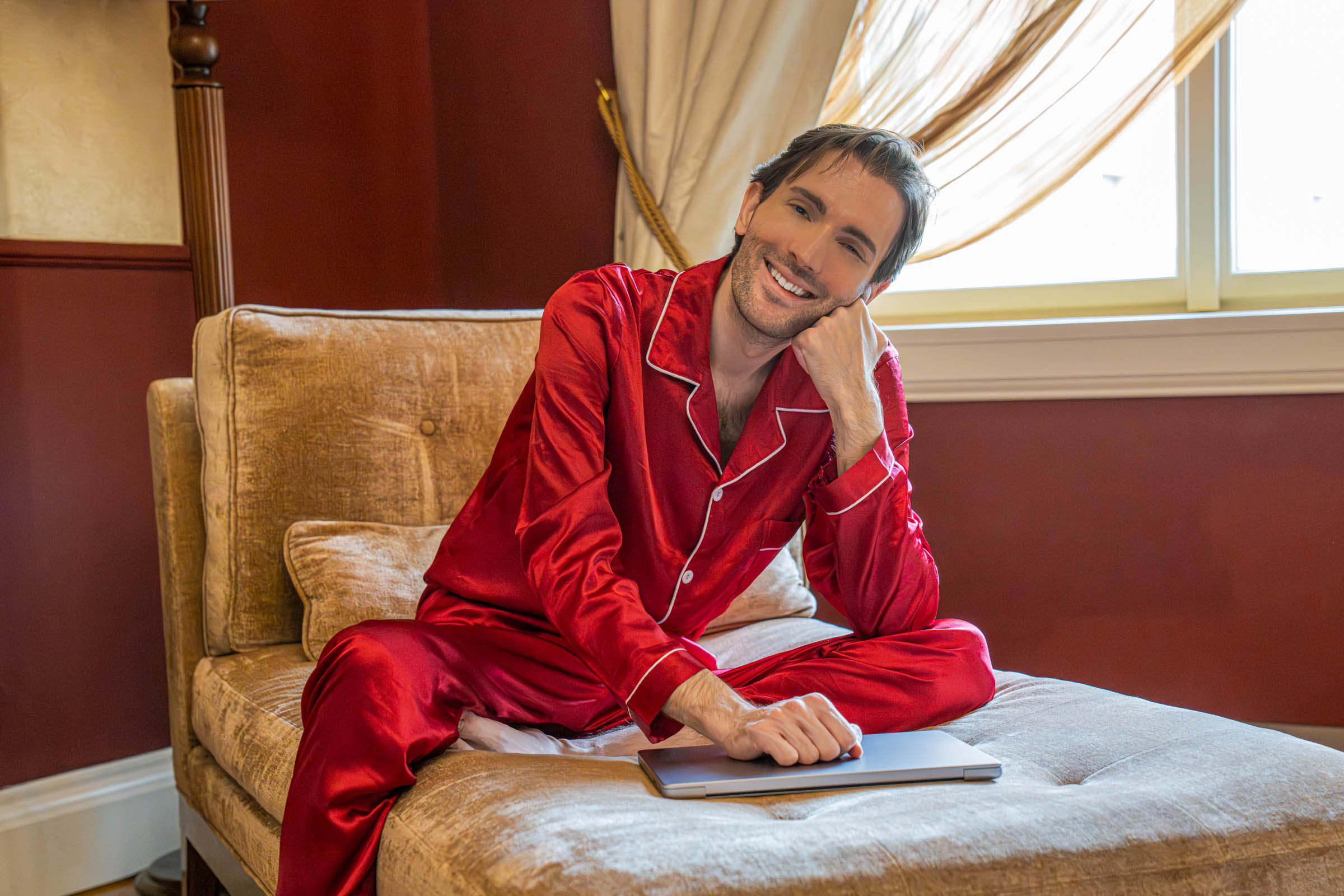 Relaxing on the velvet chaise lounge in silk pajamas with a laptop inside the Executive Suite at The Mozart Prague hotel where 18th-century baroque elegance meets modern comfort in the heart of Prague Old Town