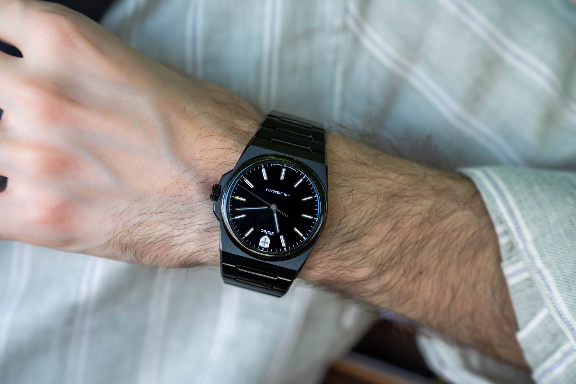 The Biatec Fusion 03 watch on the wrist of Marko Tadić, showing its black lacquered dial, applied indexes and shield logo at six o'clock, a Slovak-made automatic with Swiss Sellita SW300 TOP movement.