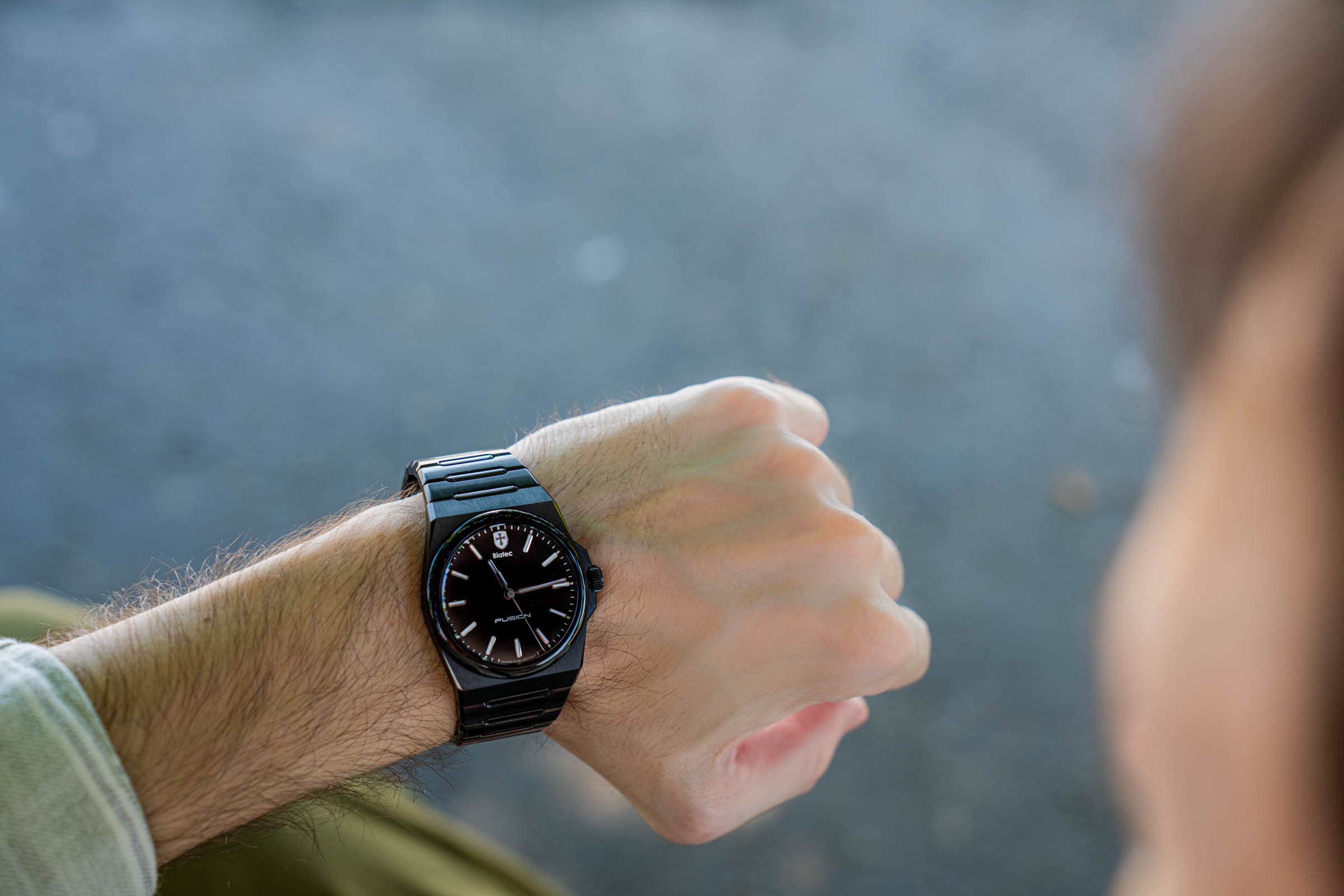 Wrist shot of the Biatec Fusion 03 automatic watch in black DLC-coated steel with integrated bracelet, worn by menswear blogger Marko Tadić against the cuff of his sage striped Giannetto Portofino shirt.