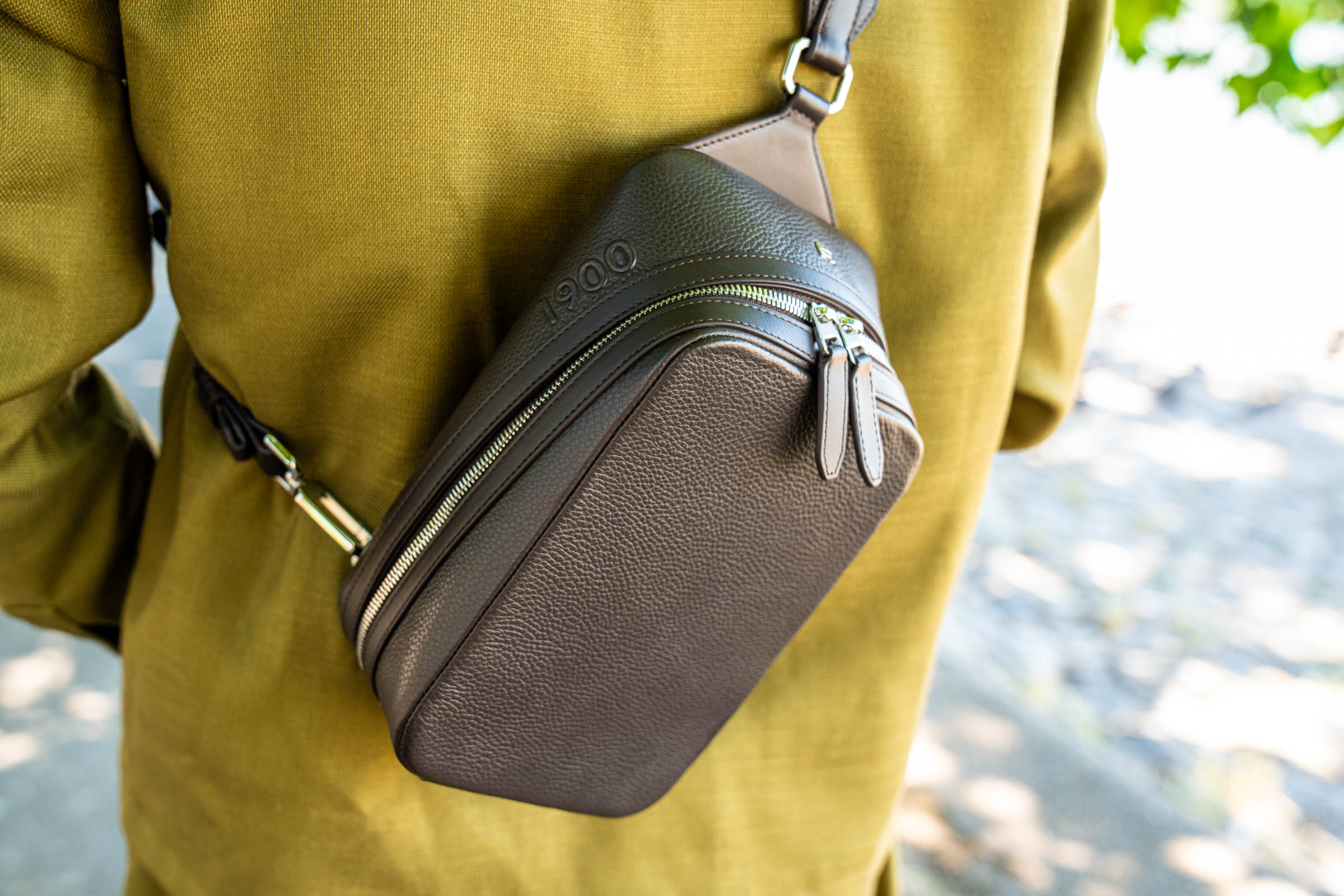 Marko Tadić stands with his back to the camera, the 1900 Tempo Grande crossbody bag resting between his shoulder blades over an olive jacket, gazing across the Danube river from Zemun quay in Belgrade.