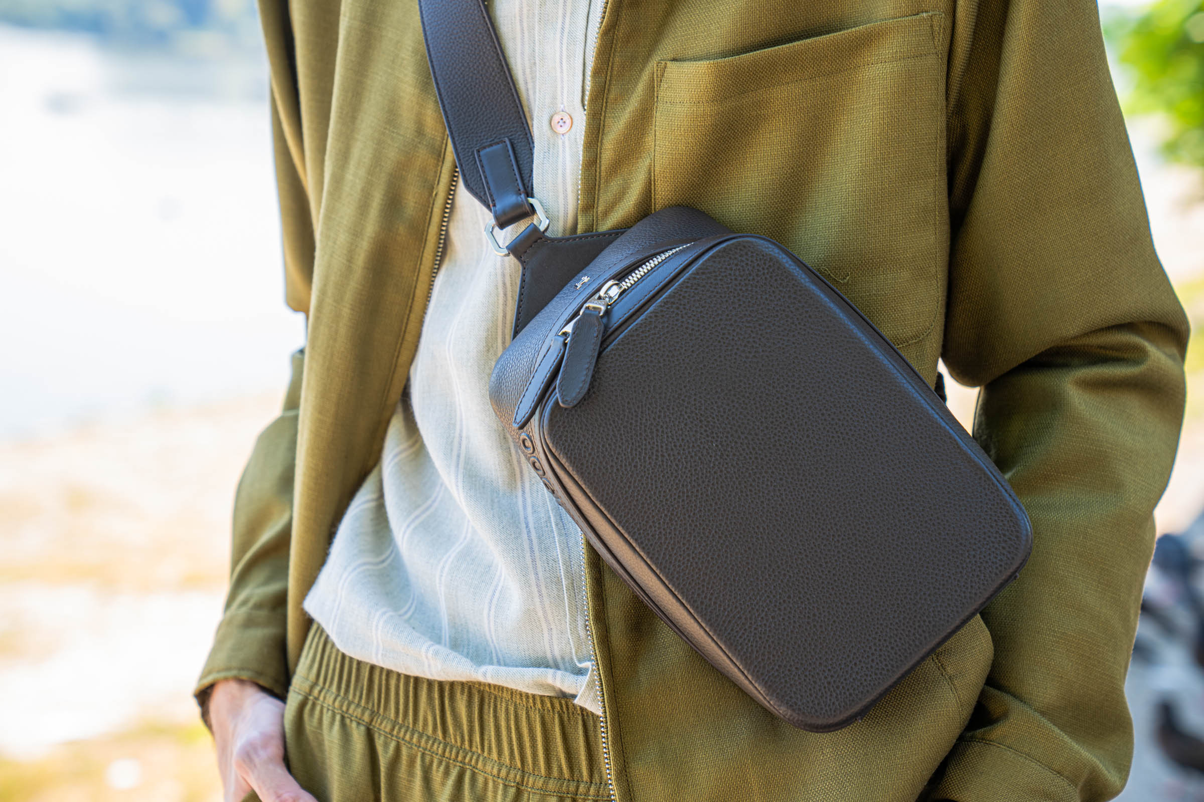 Side view of the 1900 crossbody bag's embossed leather strap falling over olive Loro Piana cargo trousers, a study in earth-tone quiet luxury styled by menswear blogger Marko Tadić on Zemun quay in Belgrade.