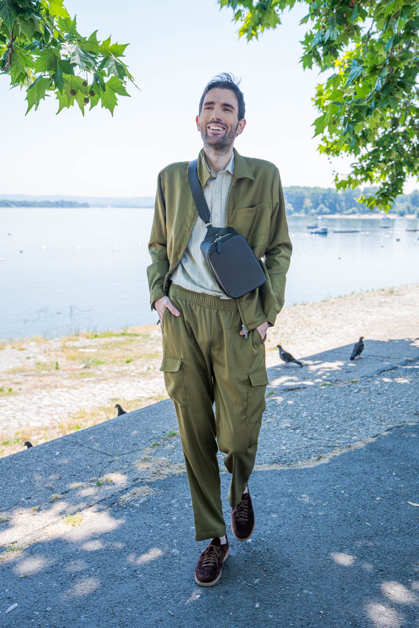Marko Tadić smiles by the Danube river wearing a Giannetto Portofino striped shirt with rolled cuffs and a black Biatec Fusion 03 watch, part of a quiet luxury summer outfit built around the 1900 crossbody bag.