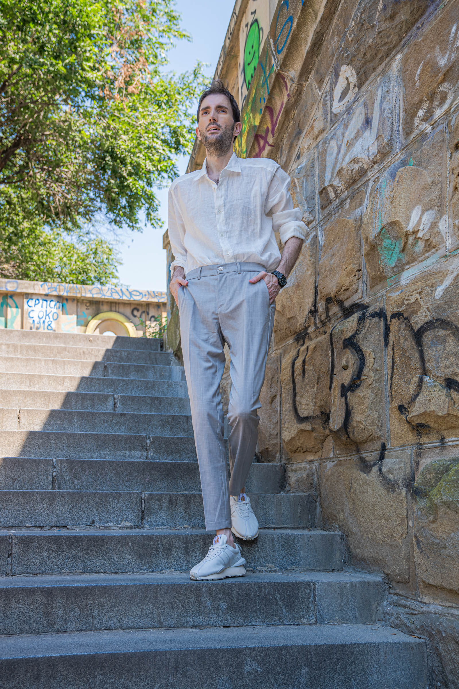 Marko Tadić, founder of the Mr.M blog, posing on Belgrade stone stairs in a light summer menswear outfit with a black Biatec watch
