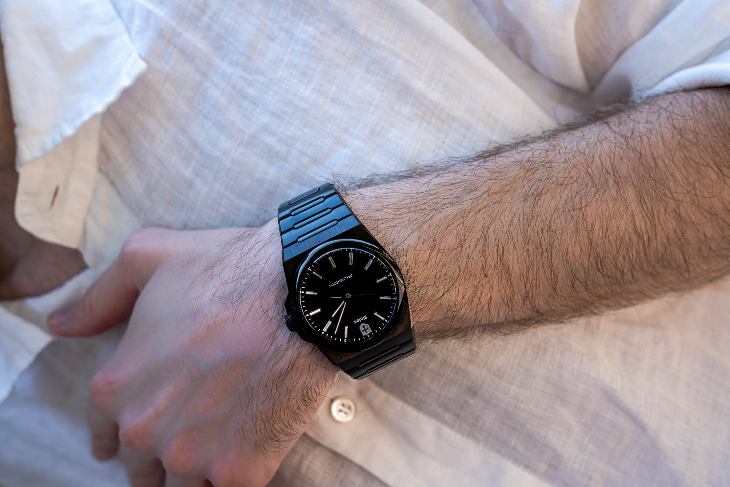 Close-up of the black Biatec Fusion 03 watch with DLC coating on the wrist of Marko Tadić, founder of the Mr.M blog, over a white linen shirt