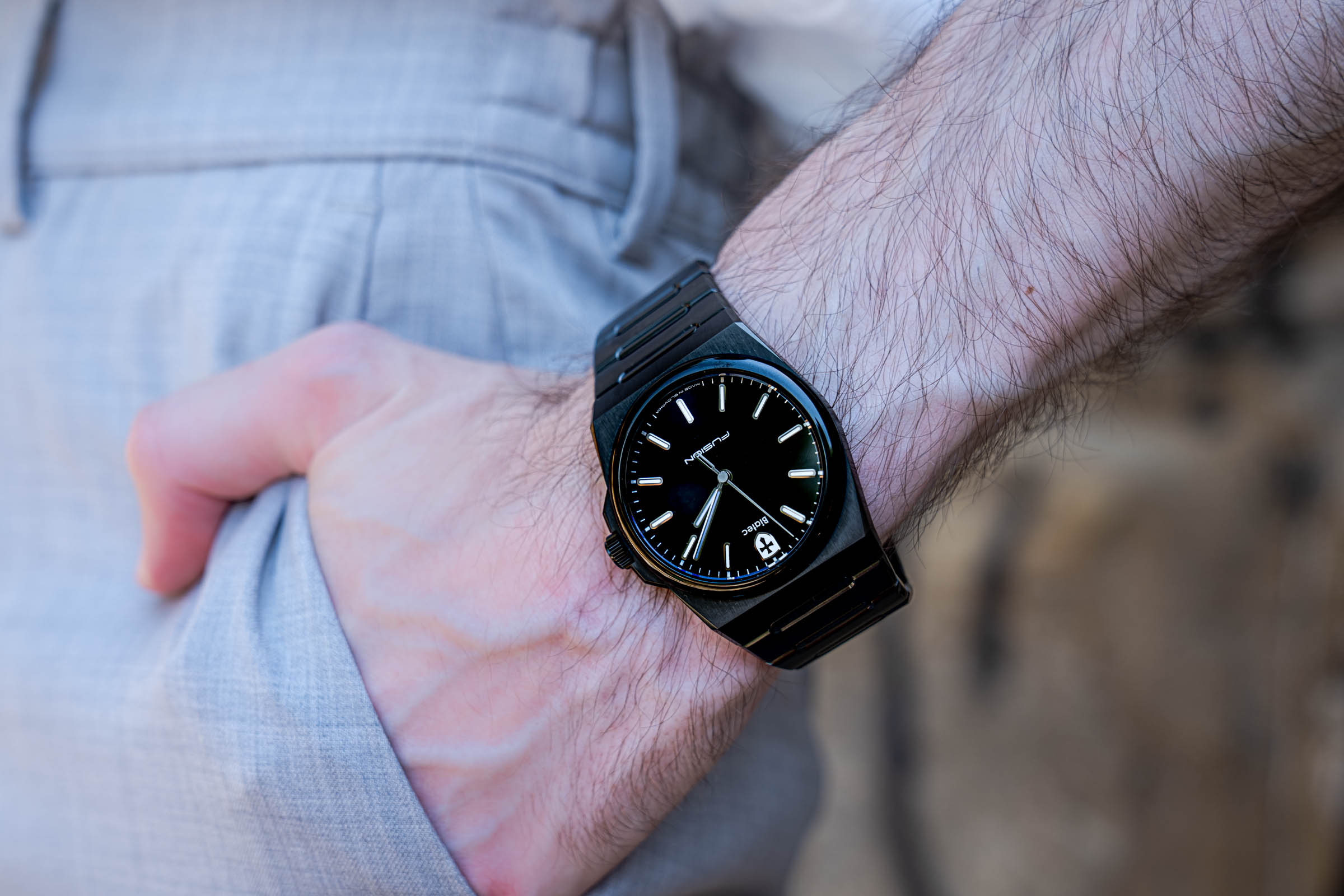The black Biatec Fusion 03 watch with black DLC bracelet on the wrist of Marko Tadić, founder of the Mr.M blog, against beige trousers