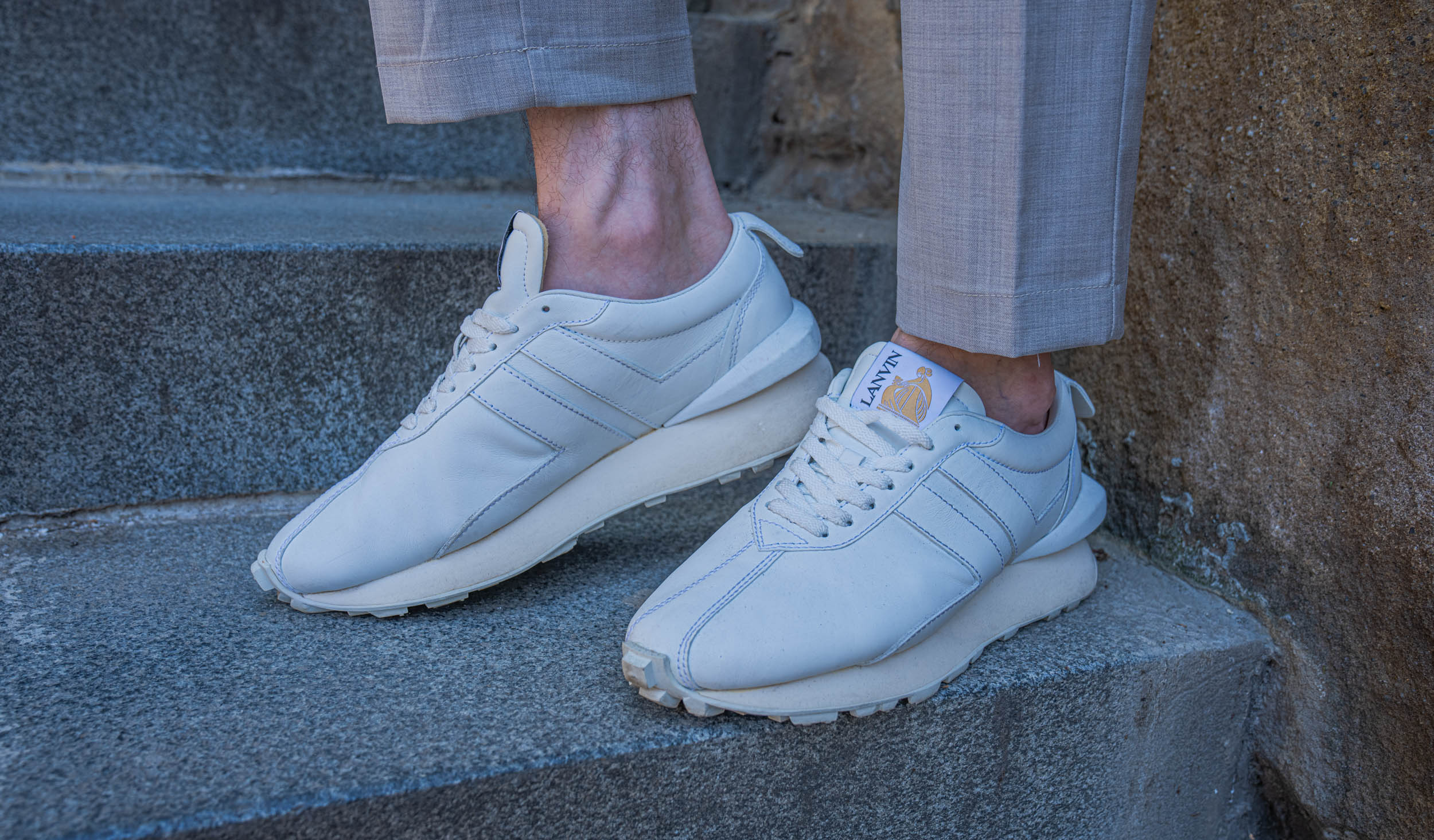 Close-up of white leather Lanvin Bumpr sneakers worn by Marko Tadić, founder of the Mr.M blog, on granite steps in Belgrade