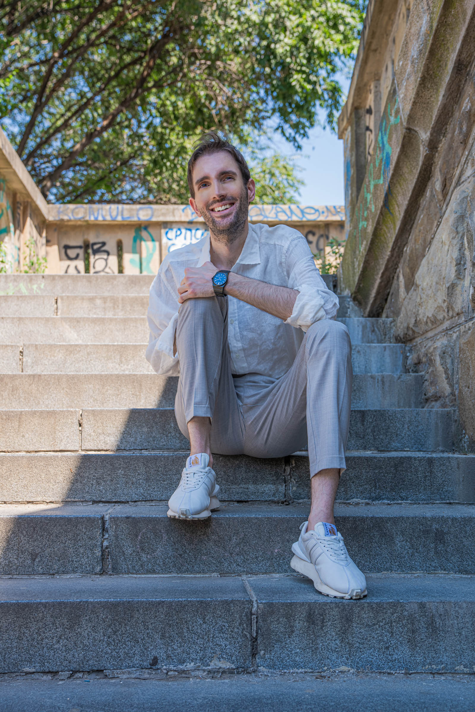 Marko Tadić, founder of the Mr.M blog, sitting on granite steps in Belgrade wearing a full summer look with the Biatec Fusion 03 watch