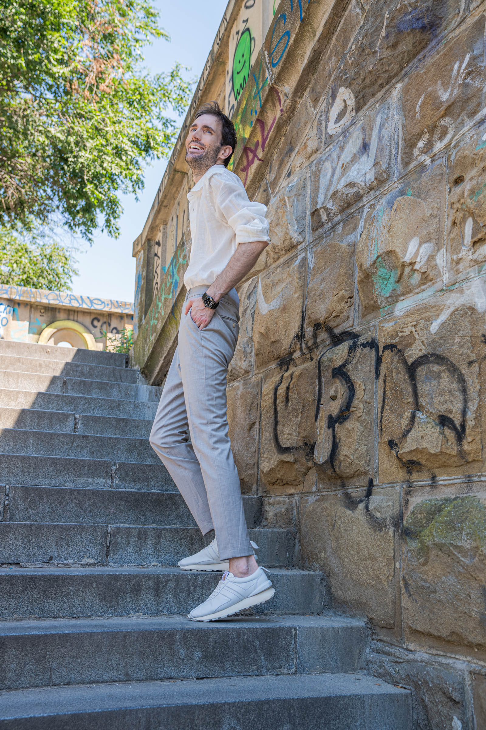 Marko Tadić, founder of the Mr.M blog, standing on old stone stairs in Belgrade wearing a white Barena Venezia linen shirt, beige trousers and white Lanvin Bumpr sneakers