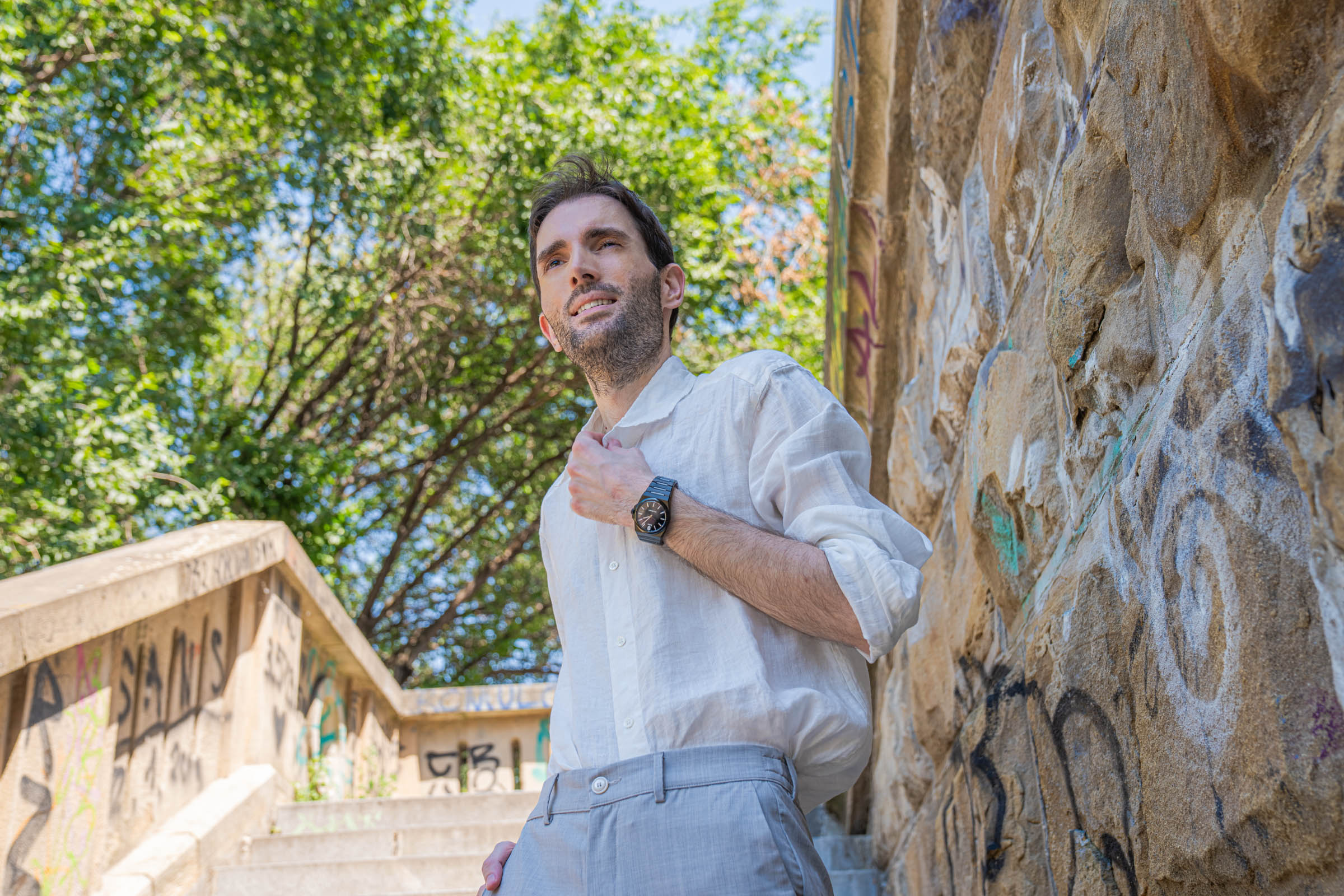 Marko Tadić, founder of the Mr.M blog, smiling on Belgrade stairs in a summer outfit with a Barena Venezia linen shirt and a black Biatec Fusion 03 watch