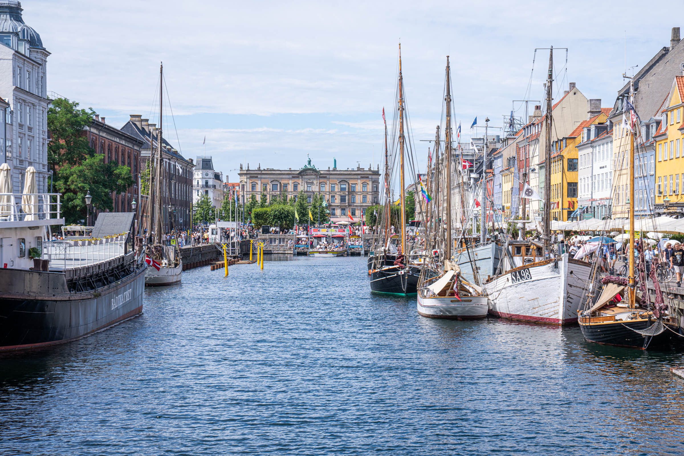 Wooden sailing ships moored along Nyhavn canal in Copenhagen with the Bådteatret theatre ship on the left