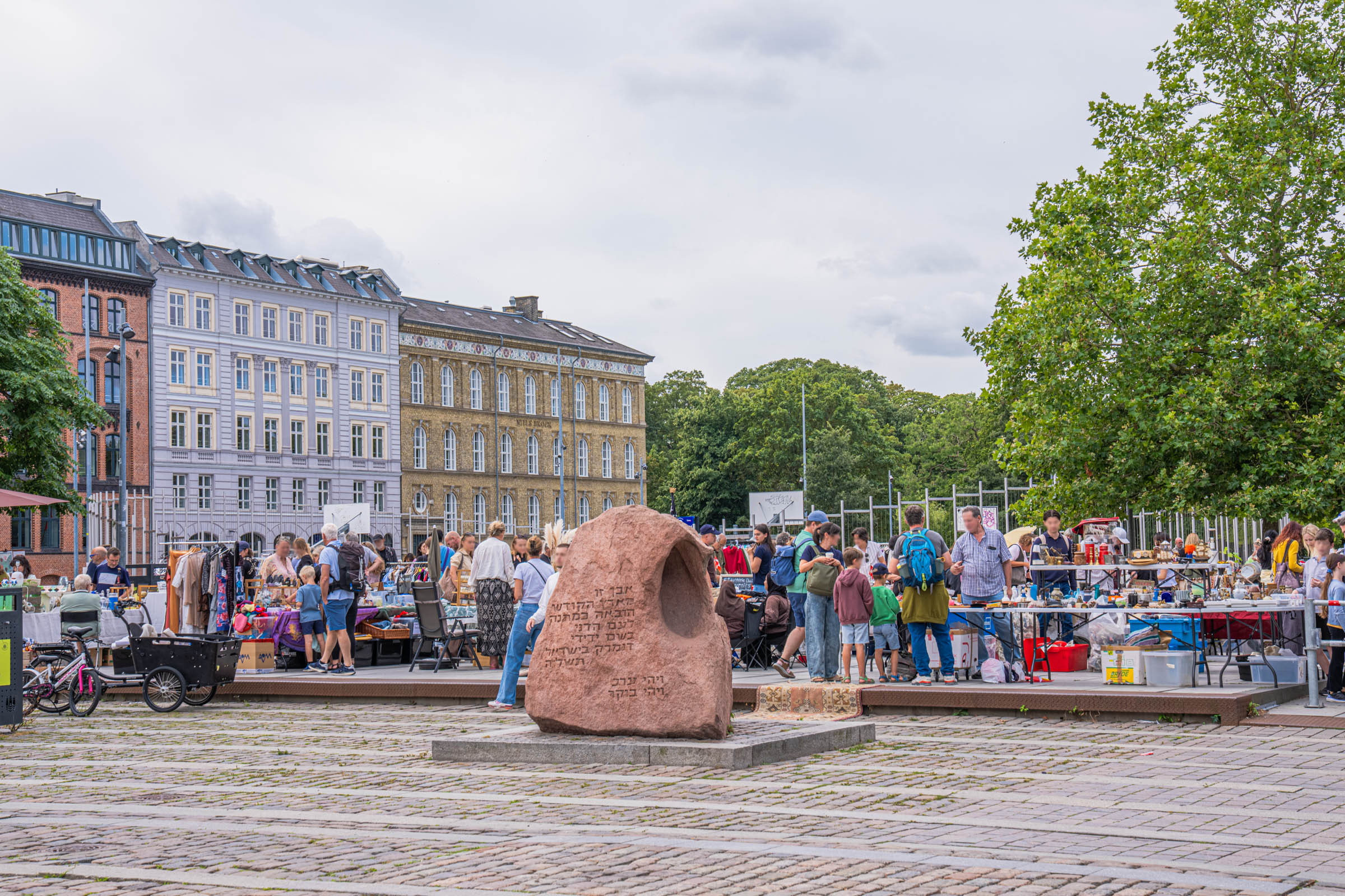 Weekend flea market on Israels Plads in Copenhagen with vintage stalls around a carved memorial stone