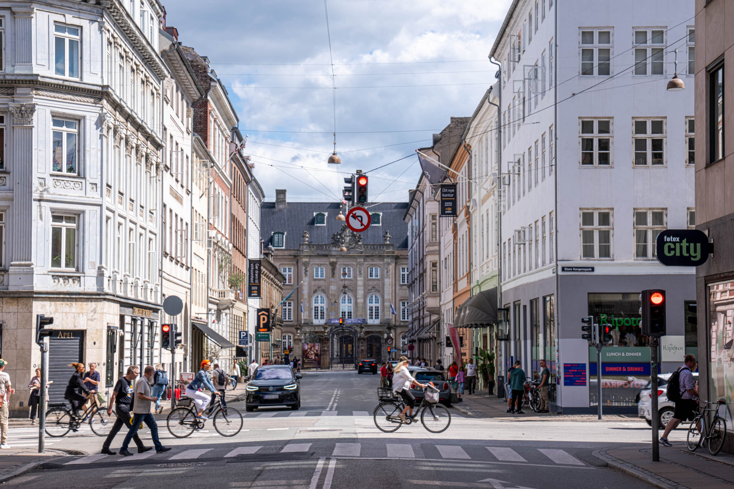Cyclists crossing Store Kongensgade in Copenhagen with a baroque palace closing the view down the street