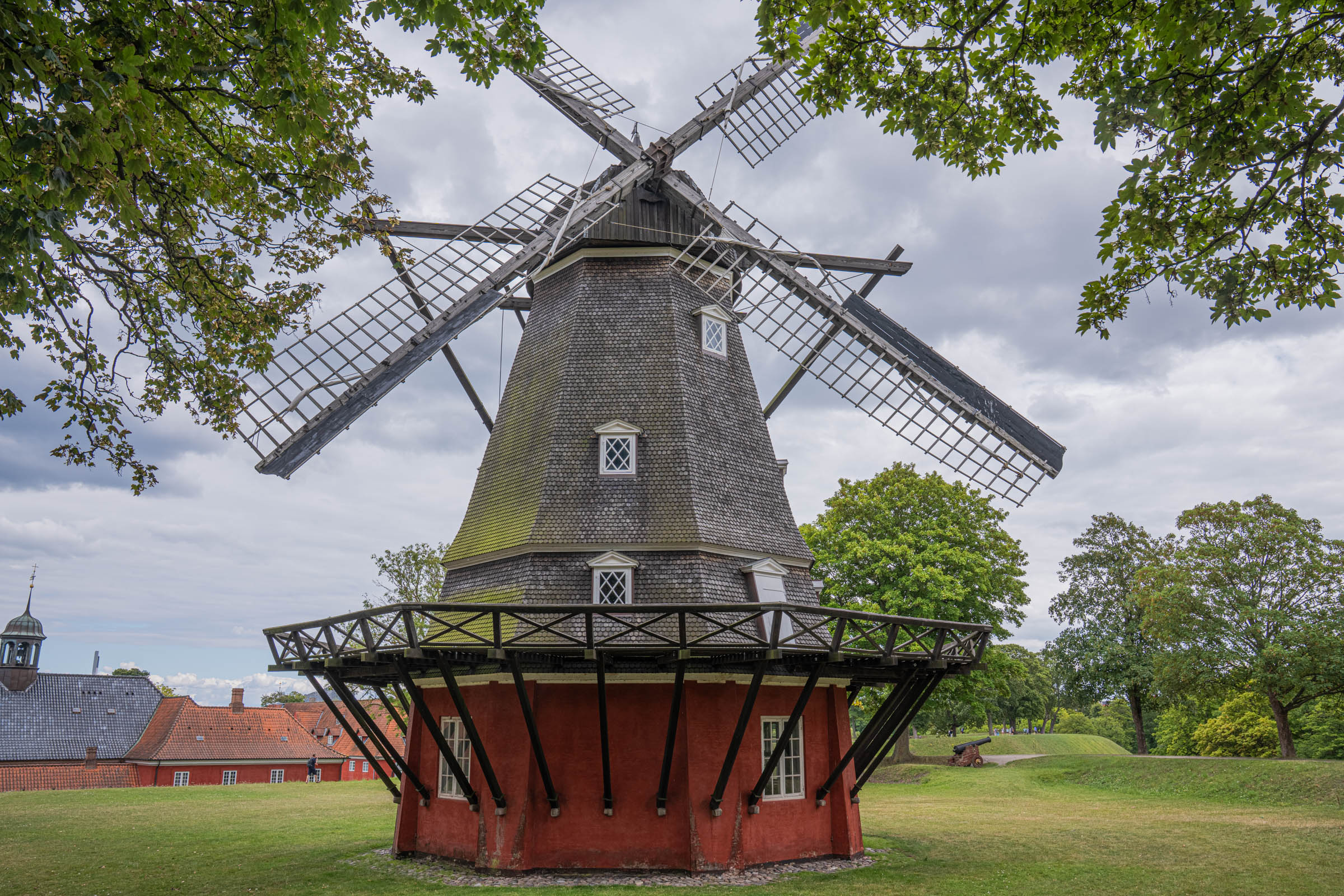 Historic wooden windmill on the ramparts of Kastellet fortress in Copenhagen with red barracks behind