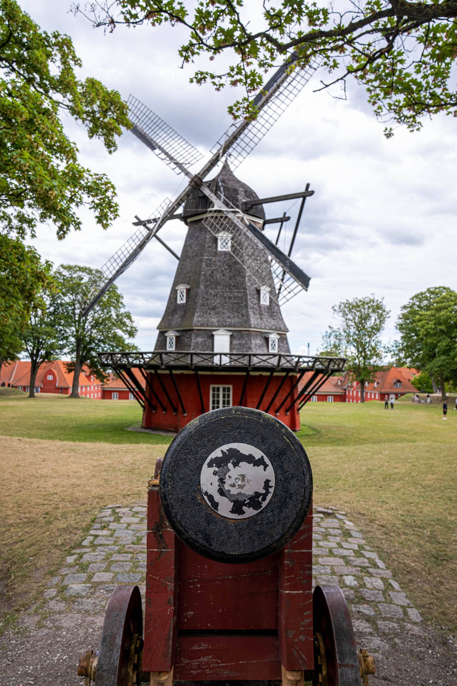 Old cannon aimed towards the Kastellet windmill and the red military barracks in Copenhagen