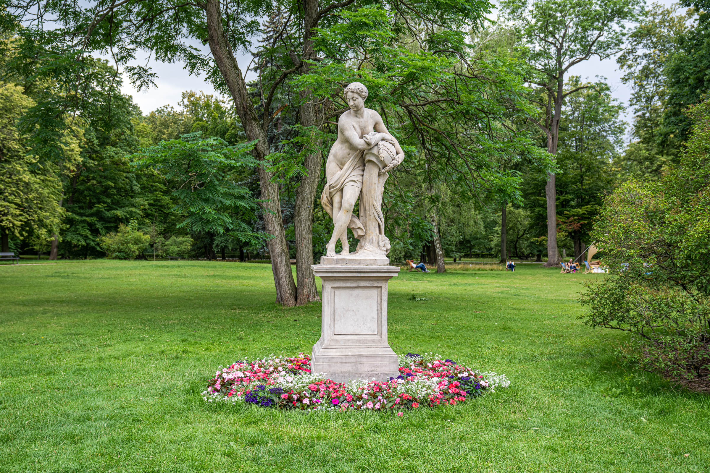 Classical marble statue ringed with flowers in Warsaw's Łazienki Royal Park, Mr.M by Marko Tadić