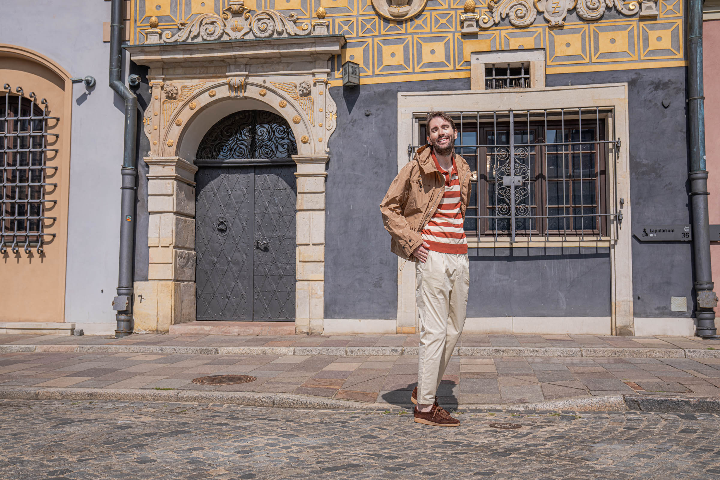 Marko Tadić in a striped polo and tan jacket outside a Renaissance house in Warsaw's Old Town, Mr.M by Marko Tadić