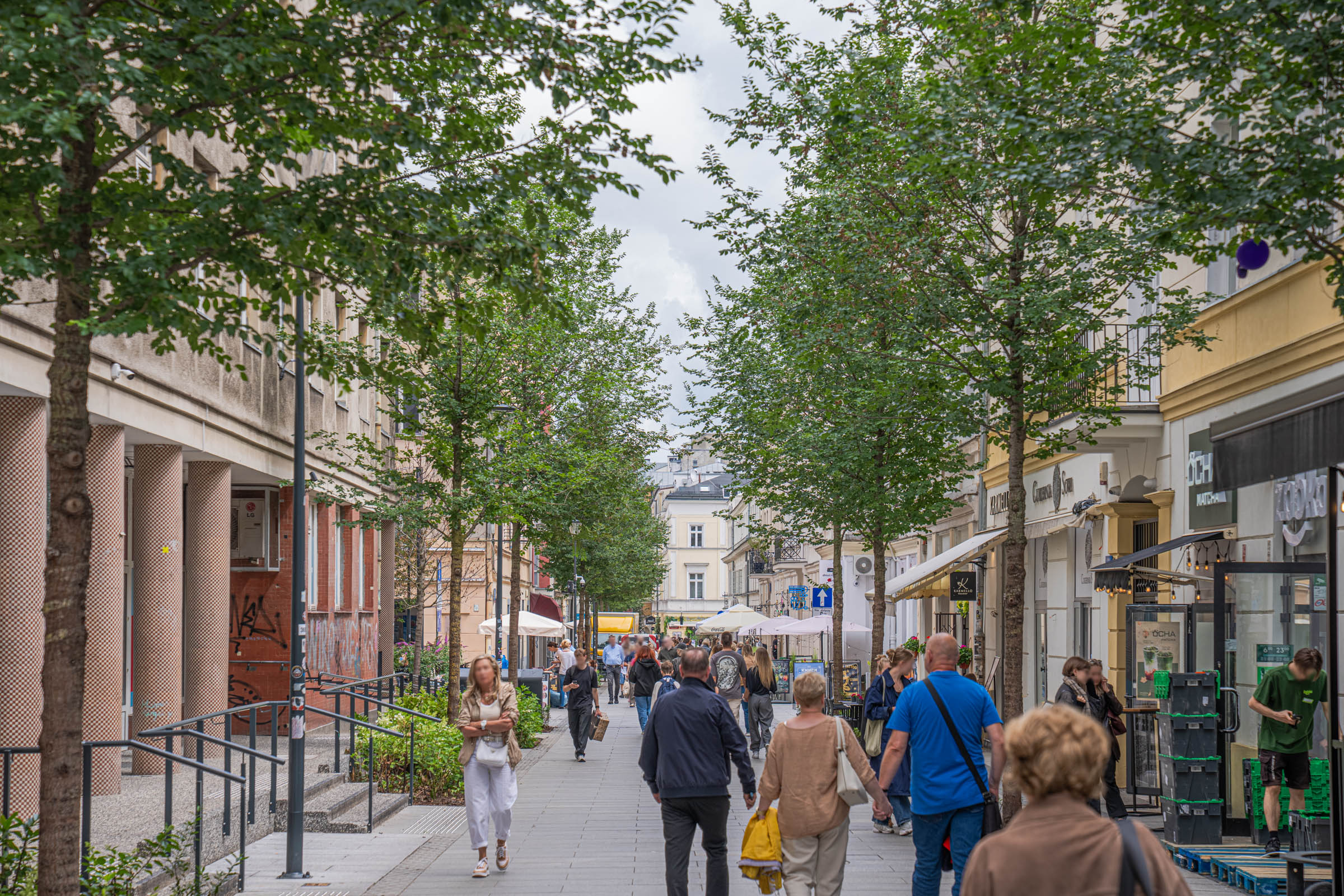 Tree-lined pedestrian shopping street in central Warsaw with cafés and boutiques, Mr.M by Marko Tadić