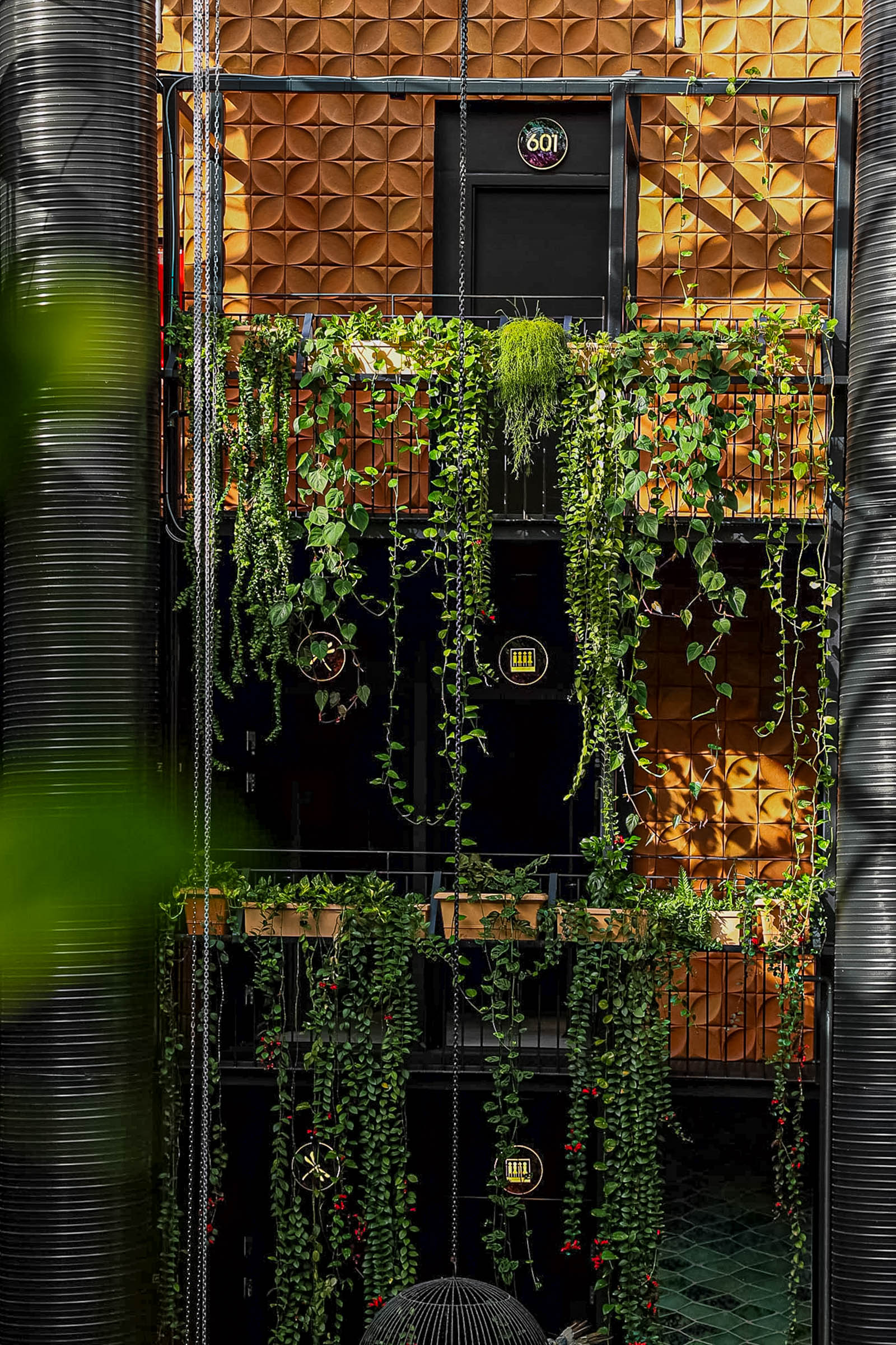 Terracotta atrium wall covered in trailing plants with illuminated room number 601 at Manon Les Suites Guldsmeden Copenhagen, photo by Marko Tadić, founder of Mr.M blog