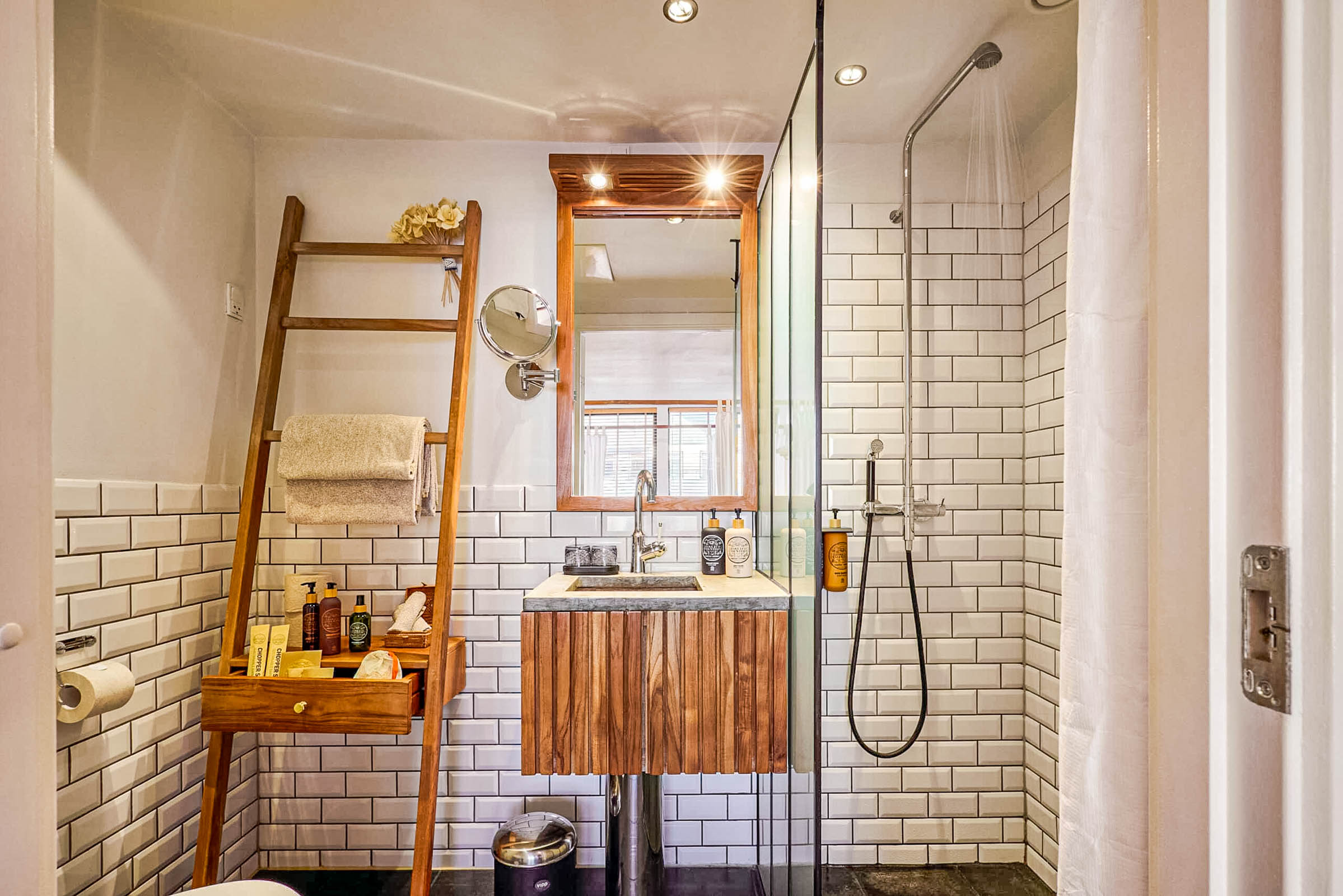 Classic Suite bathroom at Manon Les Suites Guldsmeden with white bevelled subway tiles, teak ladder shelf, stone basin and glass rain shower