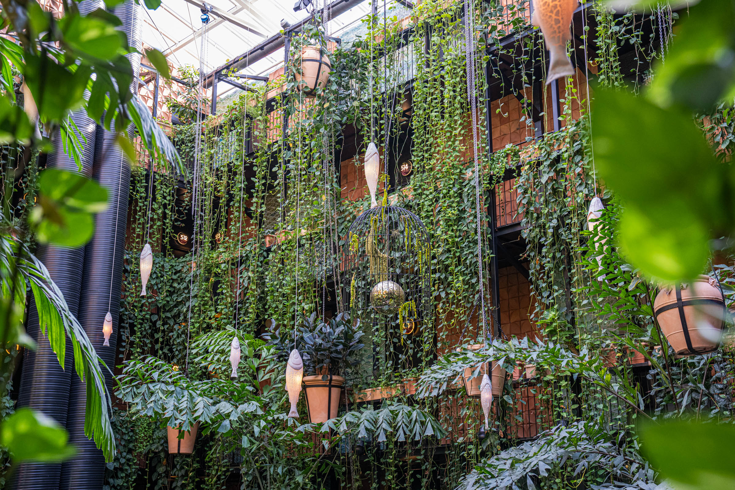 Fish-shaped lanterns, hanging vines and a birdcage chandelier in the glass-roofed atrium of Manon Les Suites, photo by Marko Tadić, founder of Mr.M blog