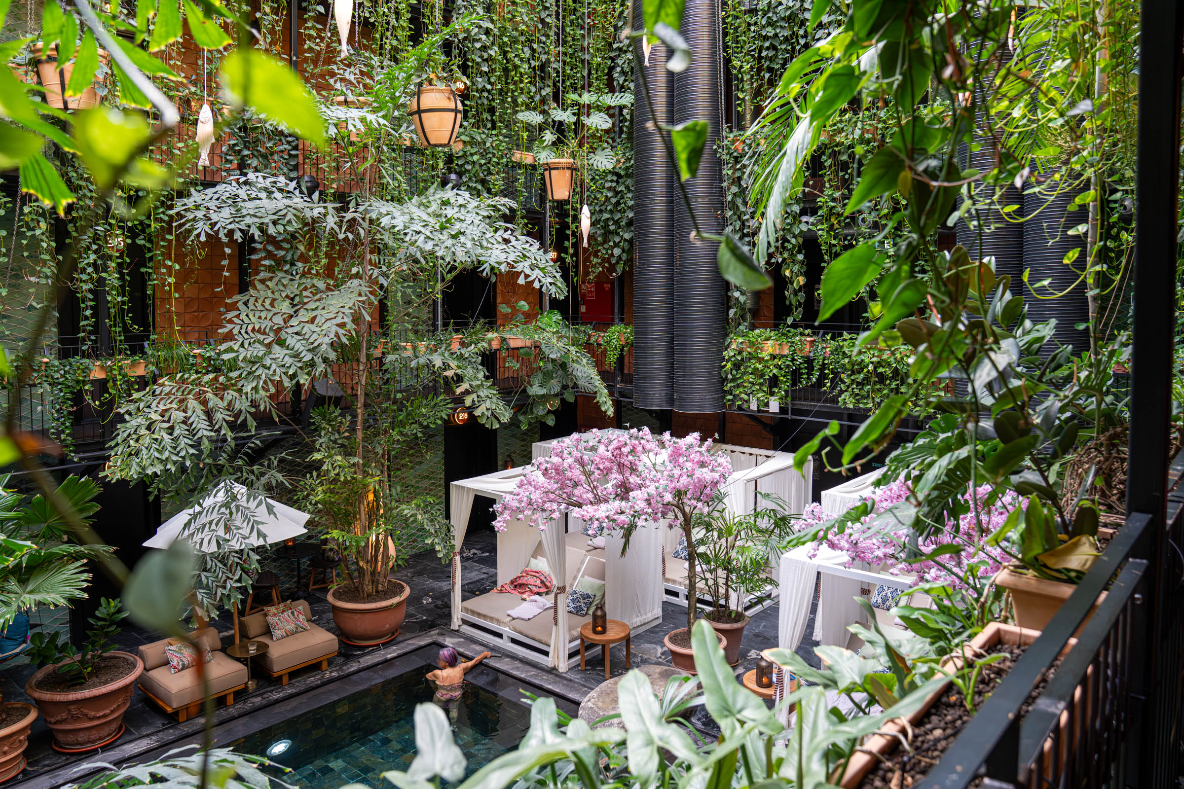 Overhead view of the Junglefish pool through hanging vines and fish lanterns at Manon Les Suites Copenhagen