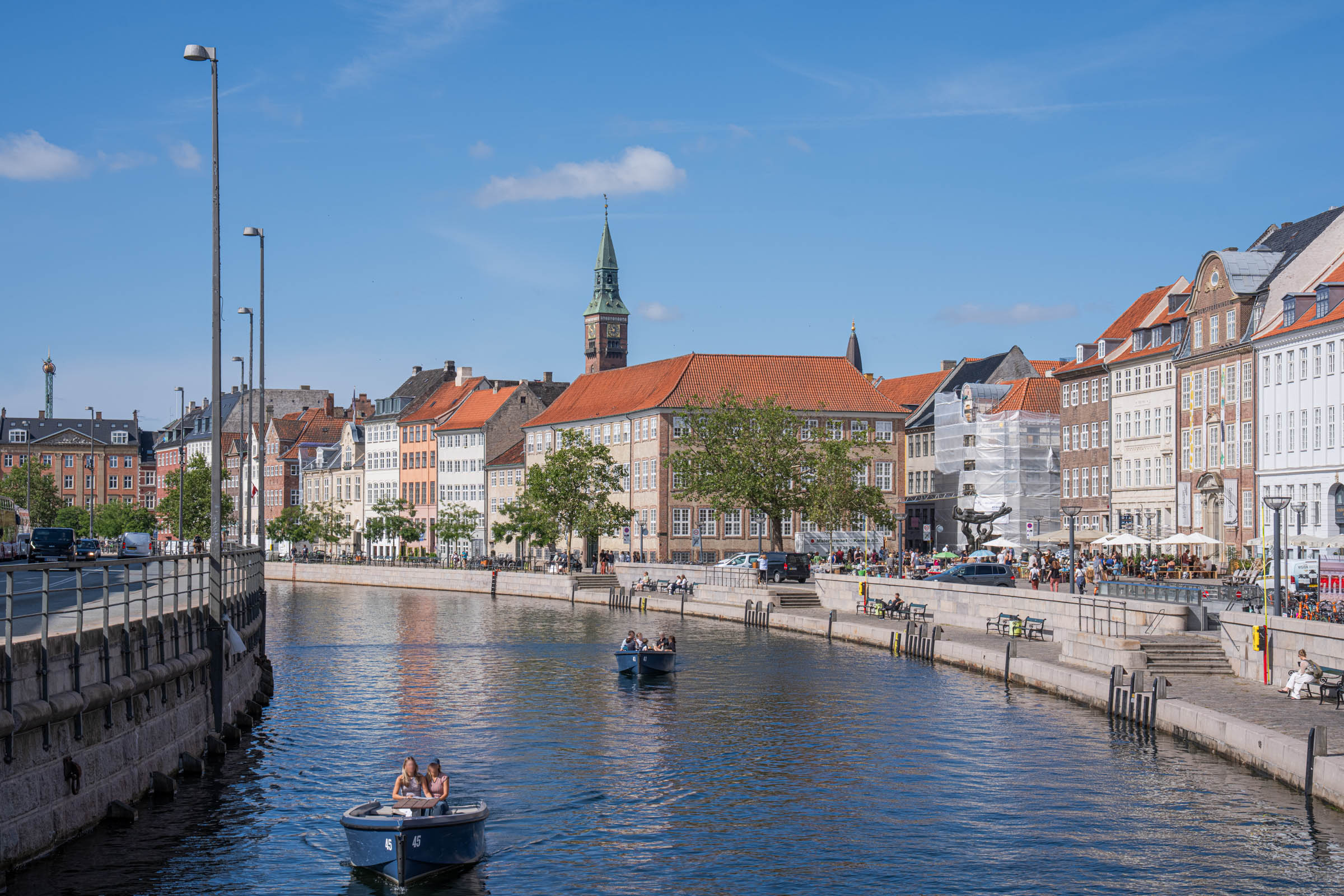 Small rental boats on a Copenhagen canal with the City Hall tower rising behind the rooftops, photo by Marko Tadić, founder of Mr.M blog