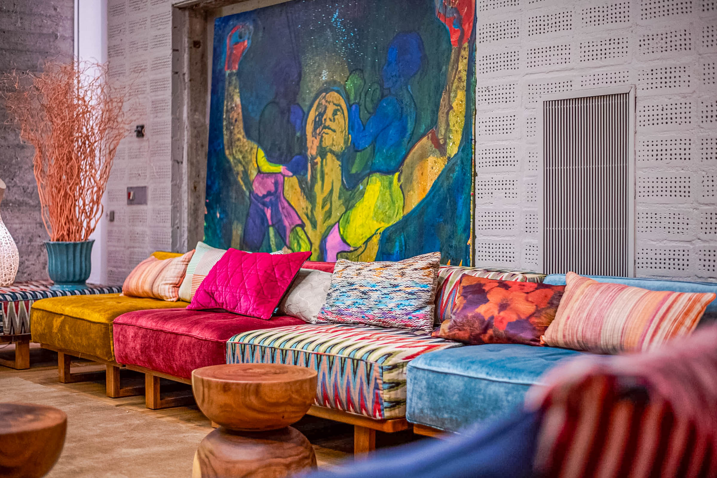 Ground floor lounge at Manon Les Suites Guldsmeden with low seating, jewel-toned cushions and a large figurative painting