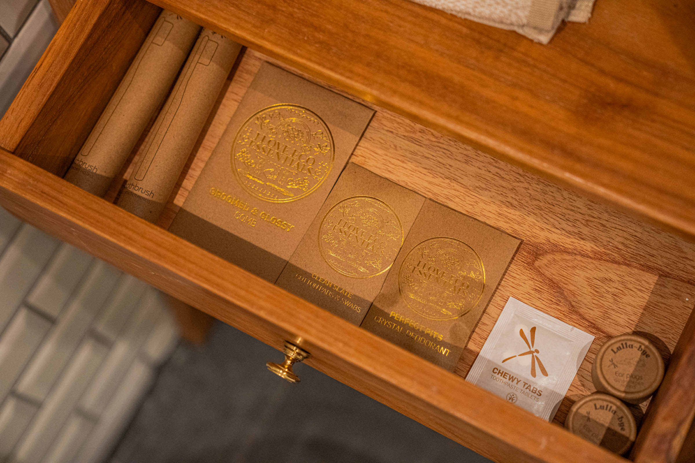 Open teak drawer with bamboo toothbrush, kraft paper comb, cotton pads, crystal deodorant, toothpaste tablets and ear plugs, photo by Marko Tadić, founder of Mr.M blog