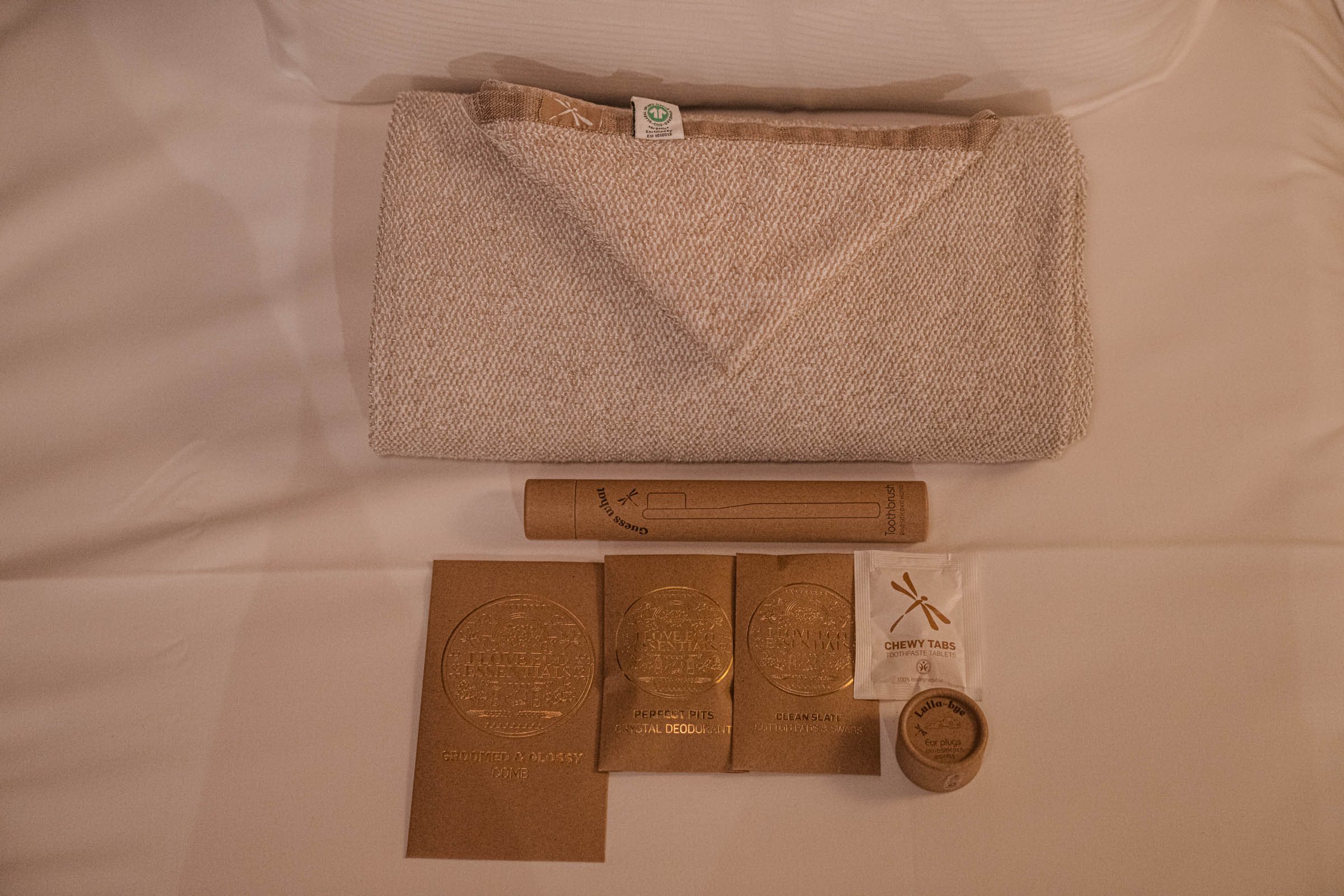 Organic cotton towel, bamboo toothbrush and plastic-free amenity set laid out on white bed linen, photo by Marko Tadić, founder of Mr.M blog