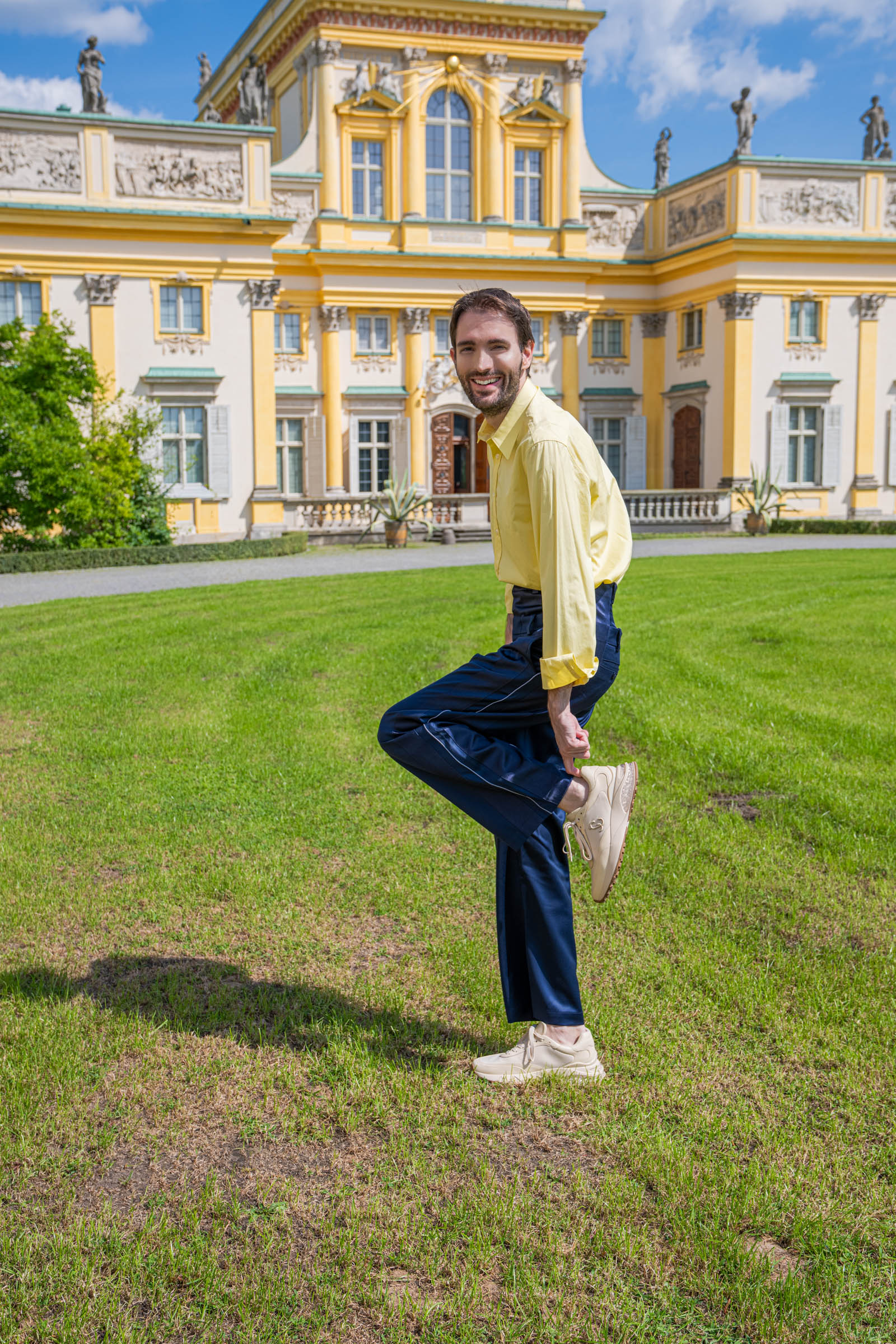 Playful pose on the Wilanów lawn revealing the cream Jimmy Choo Memphis sneaker sole and the navy trouser hem.