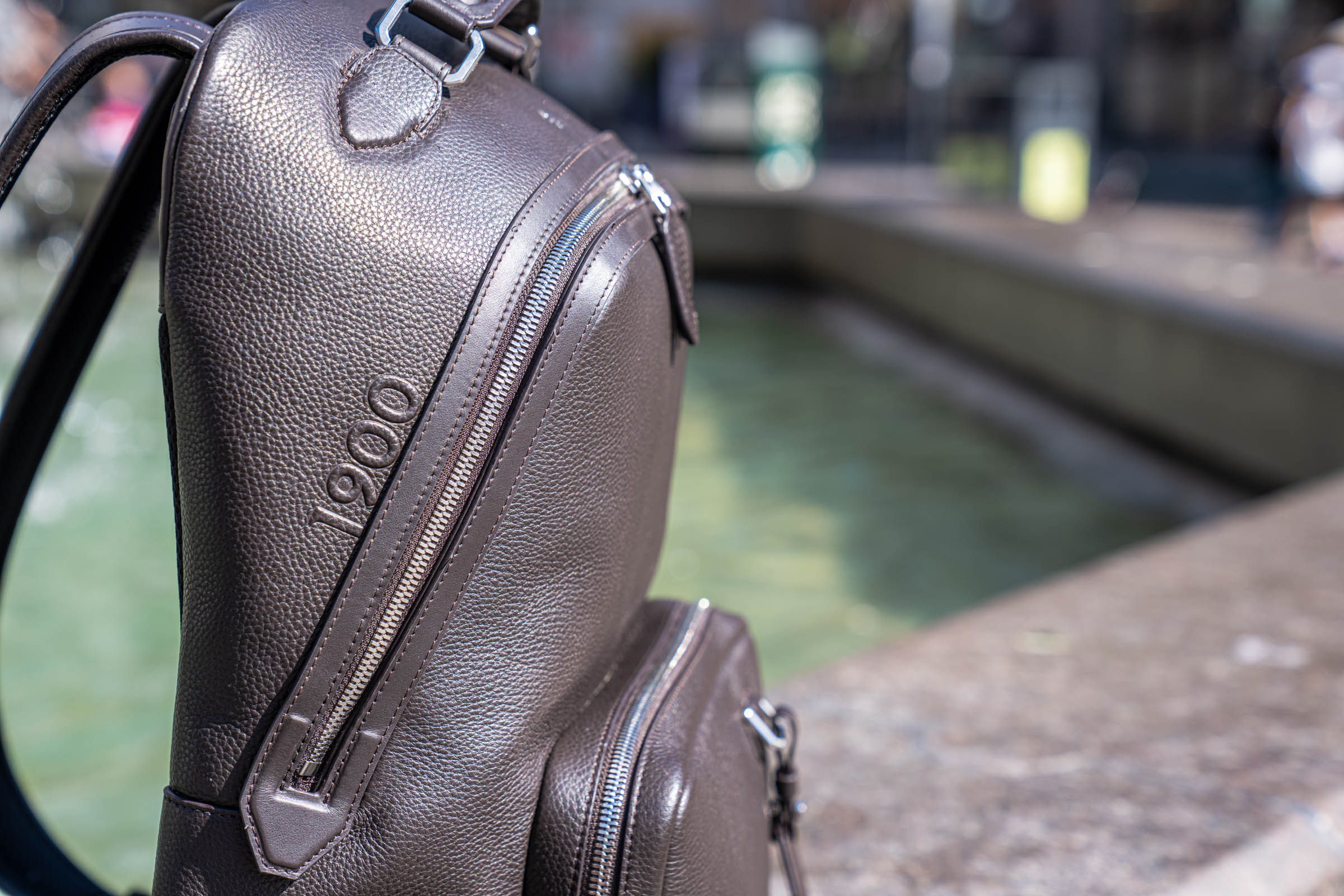 The 1900 Tempo Grande backpack in dark brown grained leather standing on the granite edge of the Caritas Fountain in Copenhagen