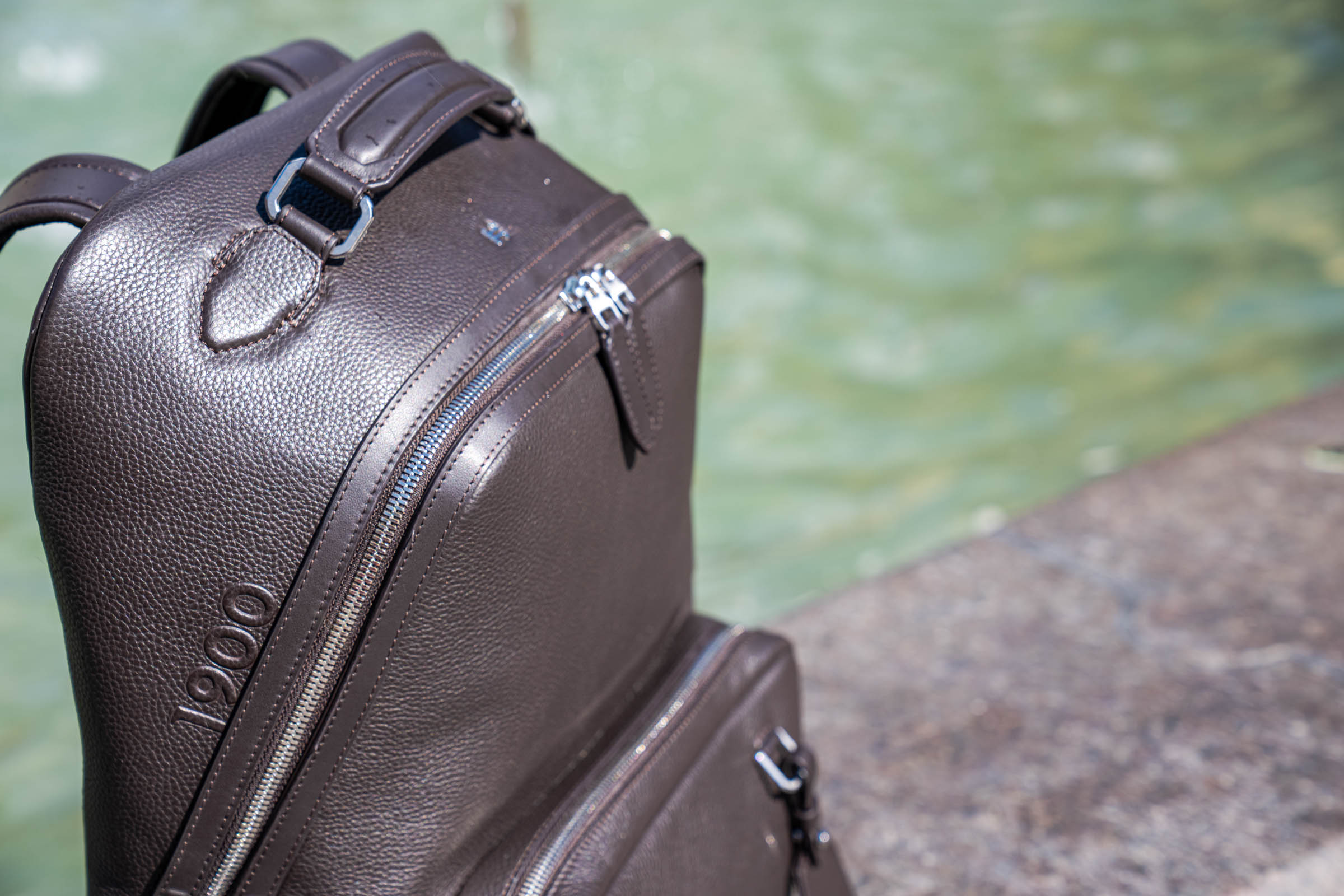 Detail of the 1900 Tempo Grande backpack showing grained calf leather, brushed leather trim, leather zip pulls and ventilated shoulder straps