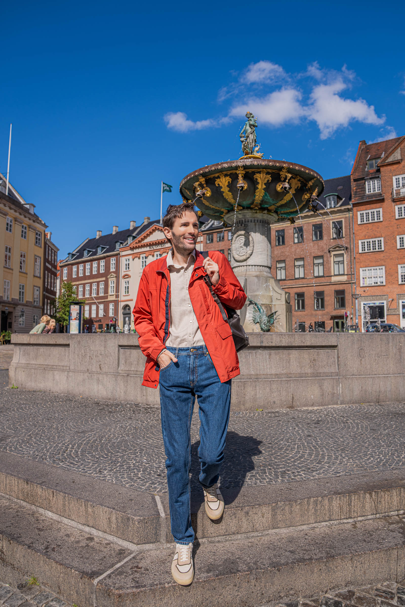 Men's smart casual outfit in Copenhagen: Marko Tadić wears a red Canali field jacket over a sand beige flannel shirt beside the 1724 inscription carved into the granite fountain basin