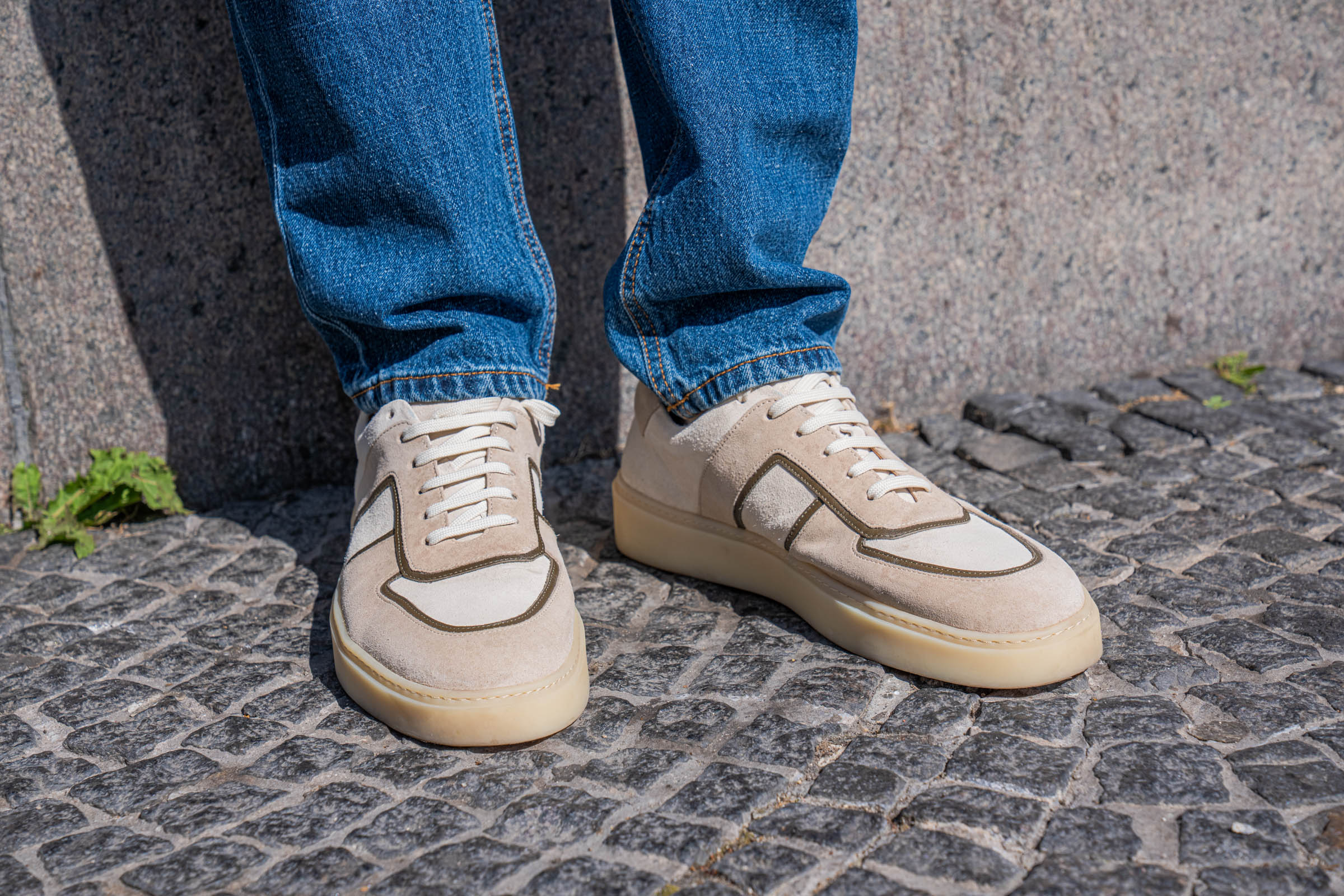 Front view of handmade Portuguese Carlos Santos leather sneakers worn with straight leg Versace denim on the granite setts of Gammeltorv