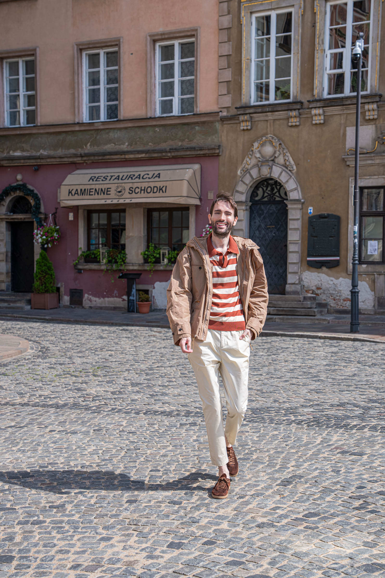 Side detail of the Ferragamo hooded jacket with drawstring hood on a cobbled Warsaw street