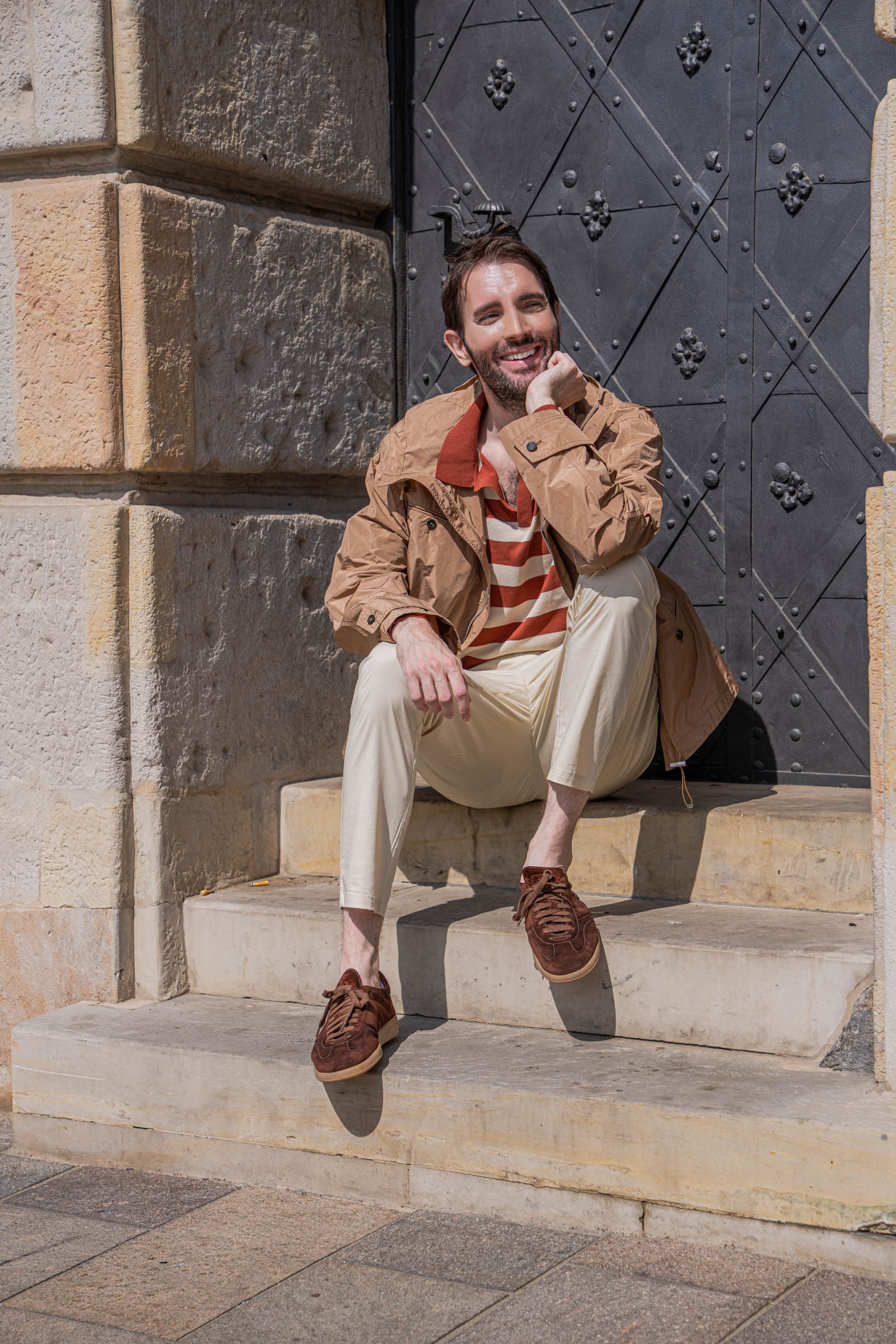 Relaxed seated portrait of Marko Tadić in cream trousers and brown suede sneakers on Old Town steps