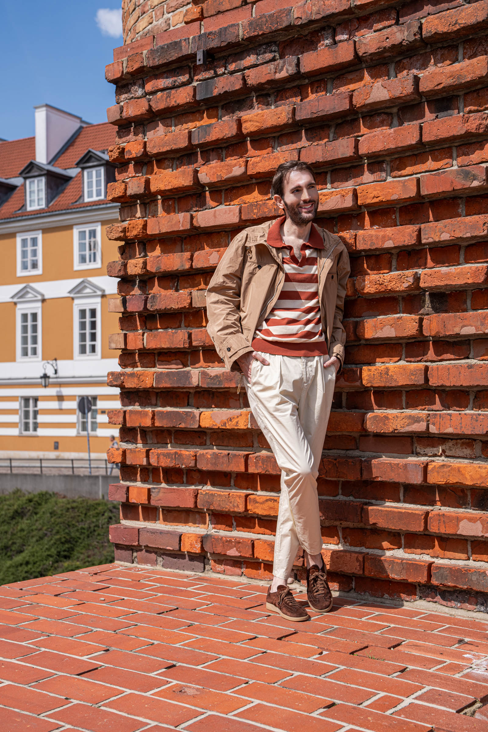Marko Tadić leaning against the red brick wall of the Warsaw Barbican in a Ferragamo hooded jacket