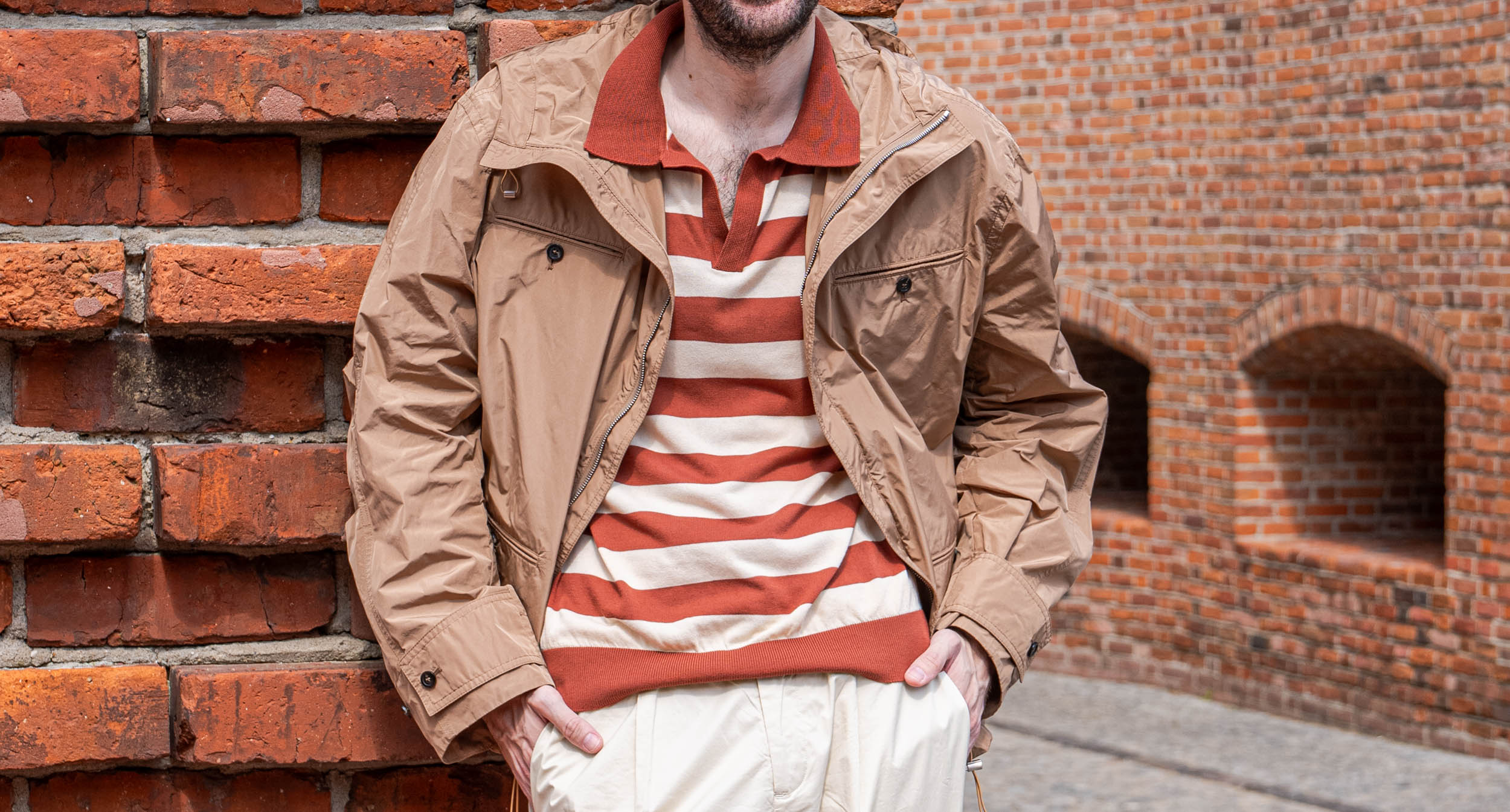 Detail of the camel Ferragamo hooded jacket worn open over a terracotta striped knit polo