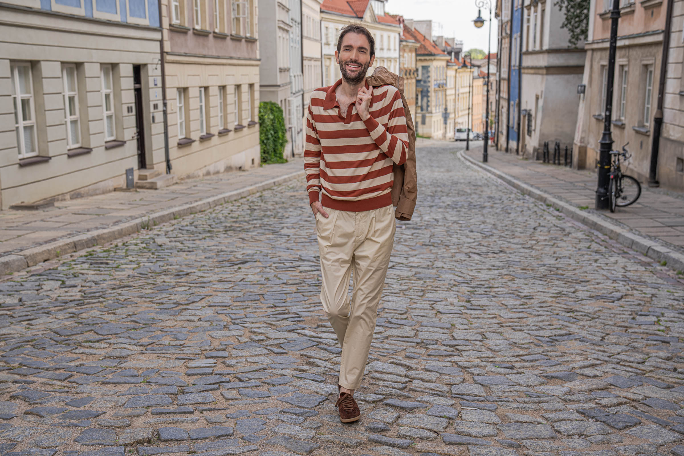 Marko Tadić walking with his Ferragamo hooded jacket slung over one shoulder in Warsaw's Old Town