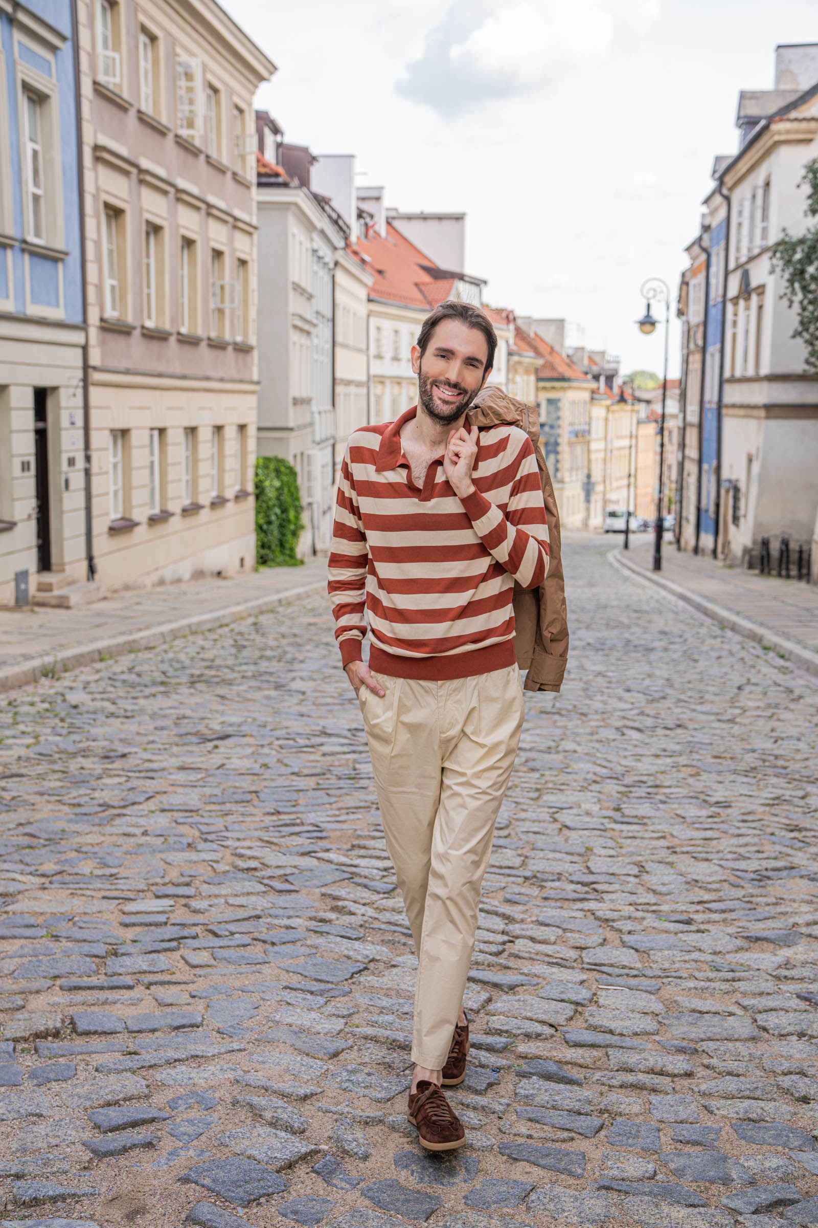 Marko Tadić walking a cobbled Warsaw street with his Ferragamo jacket over one shoulder