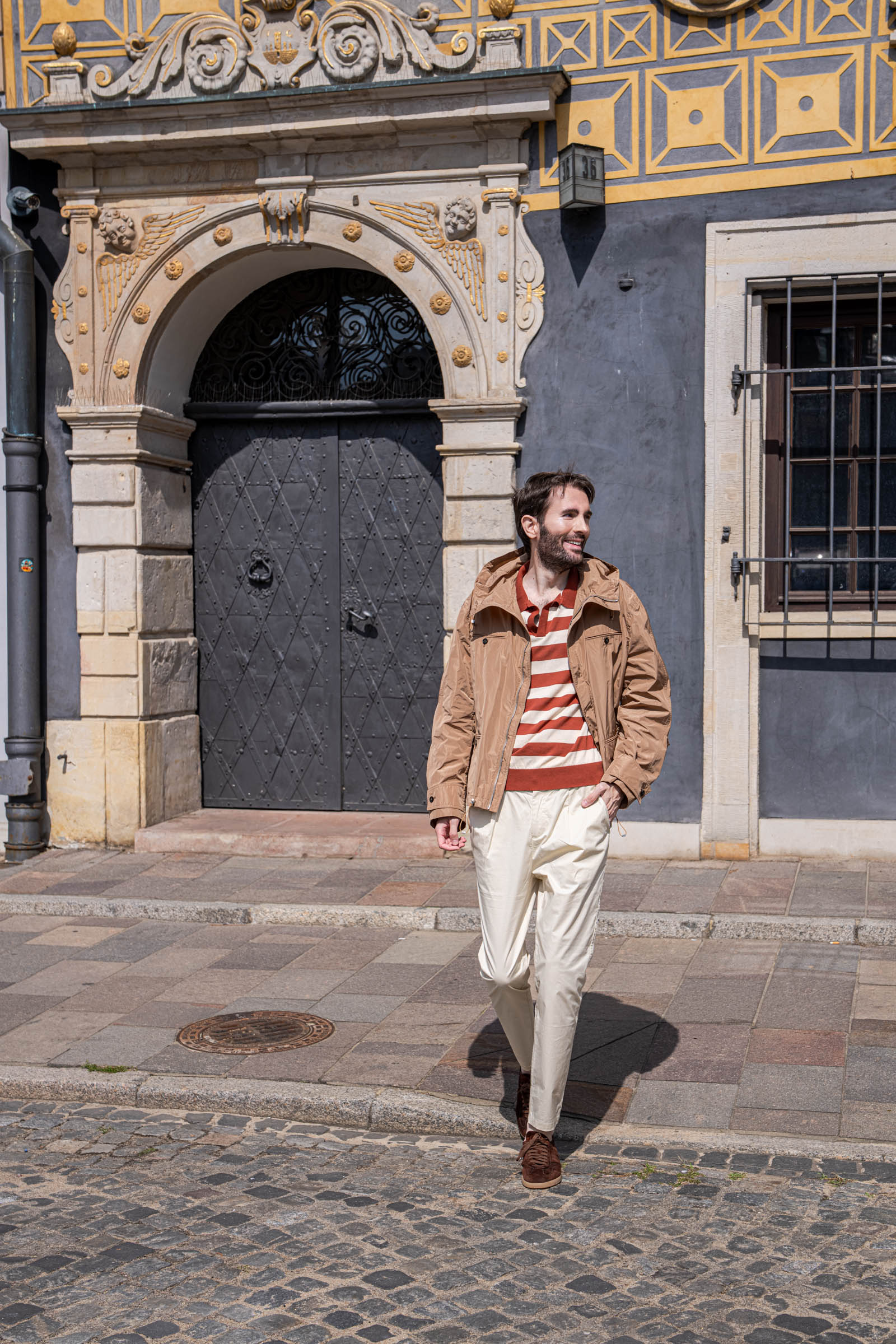 Front view of Marko Tadić in a Ferragamo hooded jacket, terracotta striped polo and Santoni Oly suede sneakers